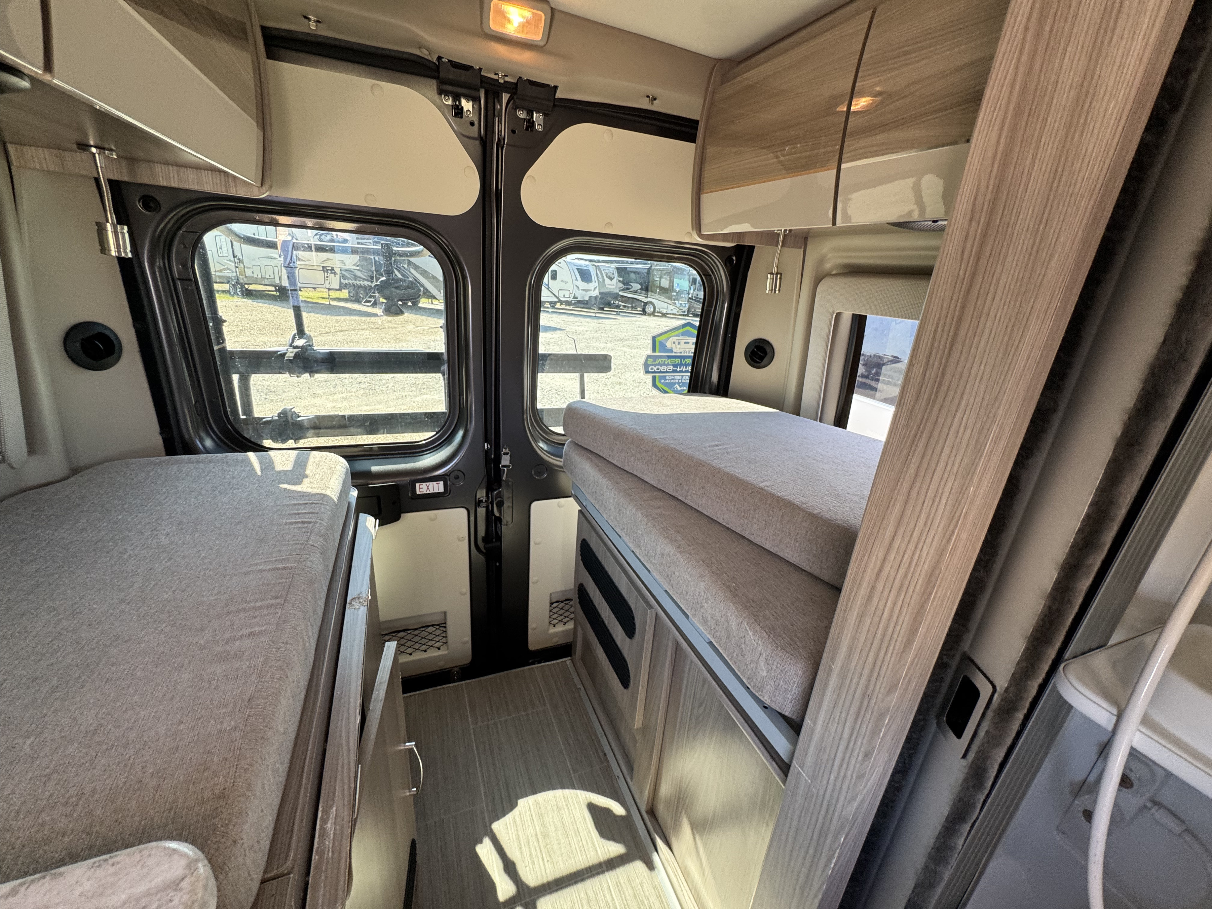 Explore this RV rental camper van interior featuring comfortable beds, overhead storage, and rear doors for your next adventure.. Thor Scope 2023