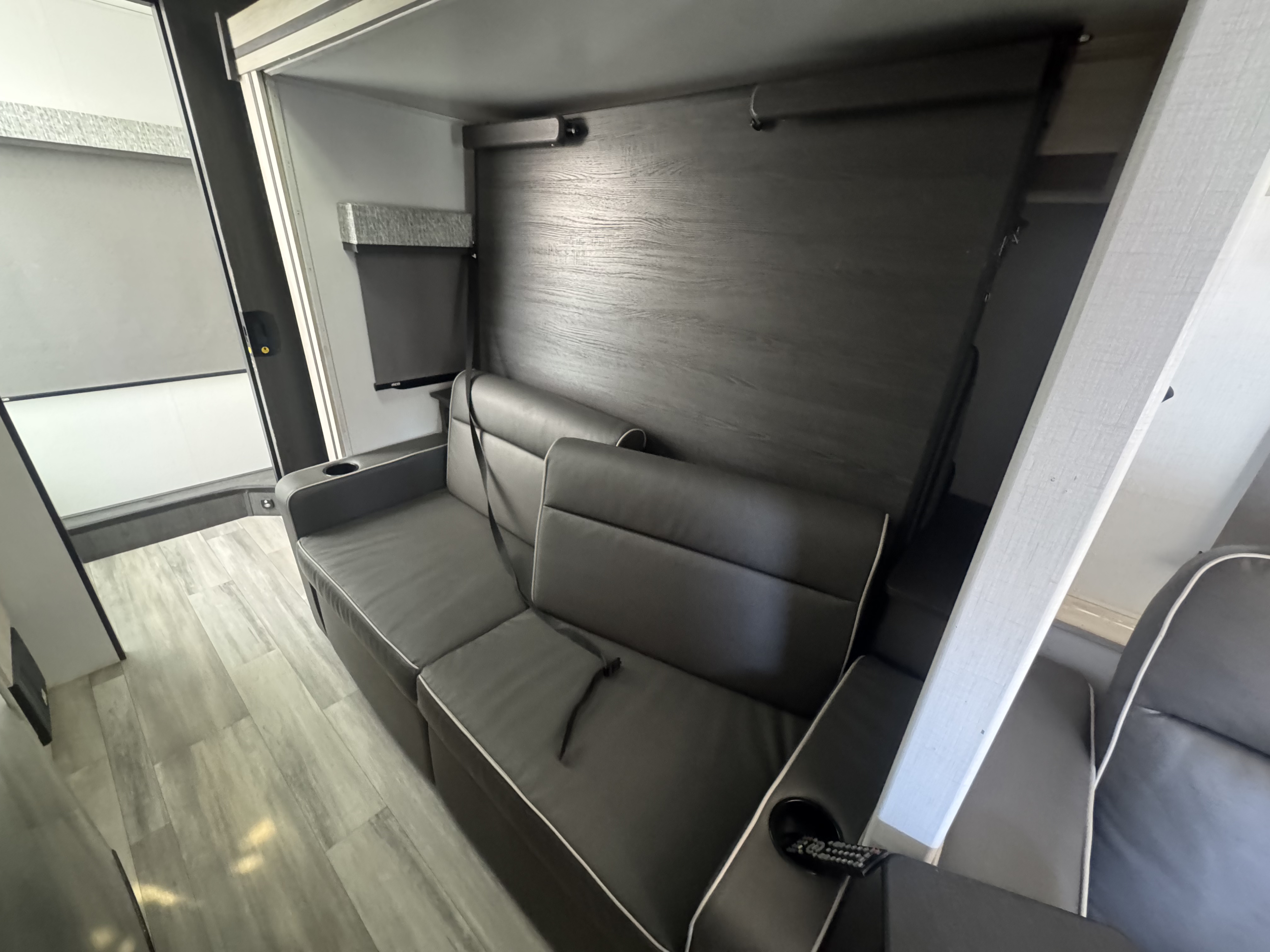 RV rental: Modern grey sofa with cupholder & seatbelt in a sleek interior, featuring a wall that likely folds down into a bed.. Forest River Sunseeker MBS 2023