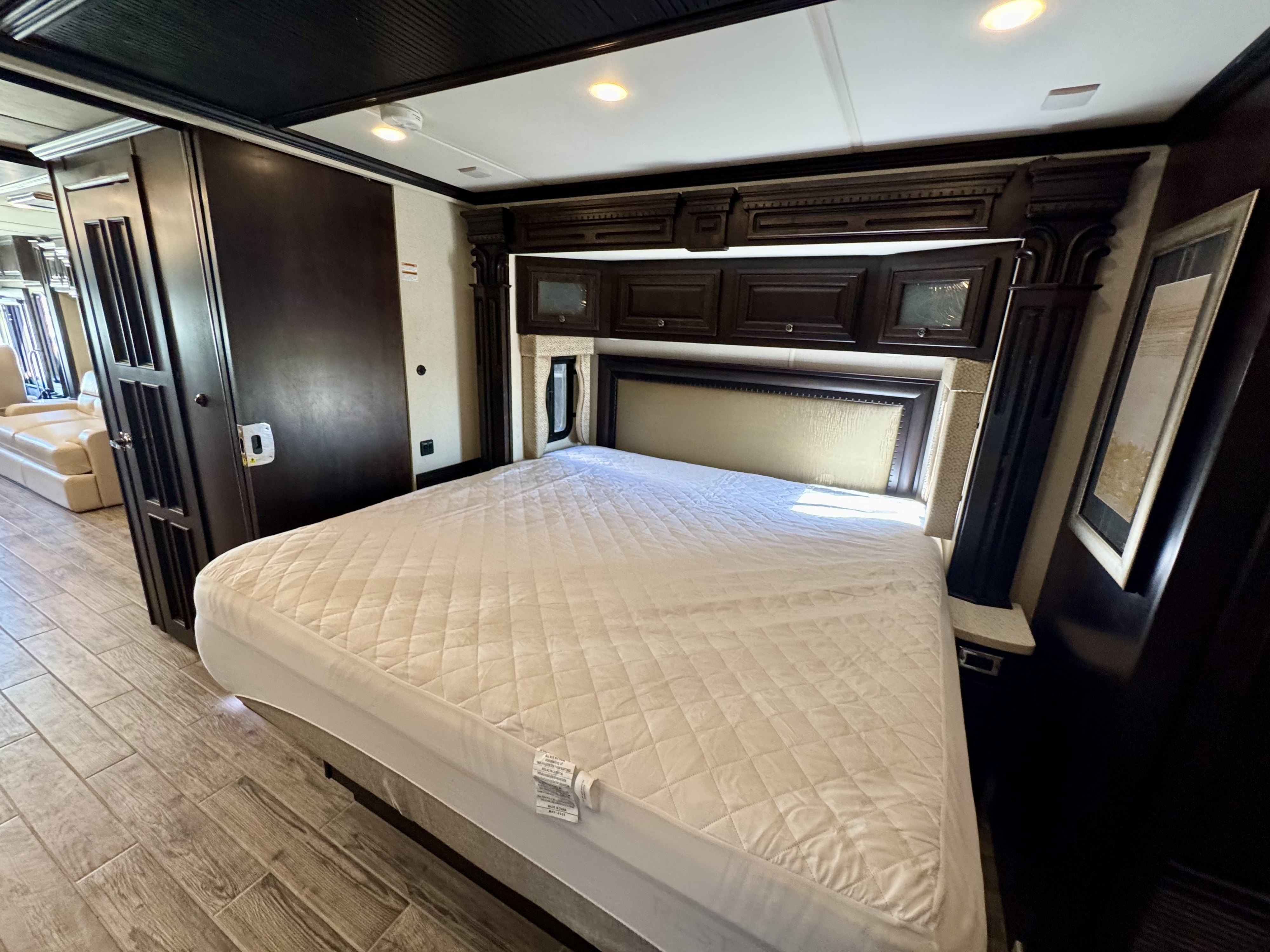 RV rental: Spacious bedroom featuring a comfortable bed, elegant dark wood cabinetry, overhead storage, and tiled flooring.. Newmar Dutch Star 2017