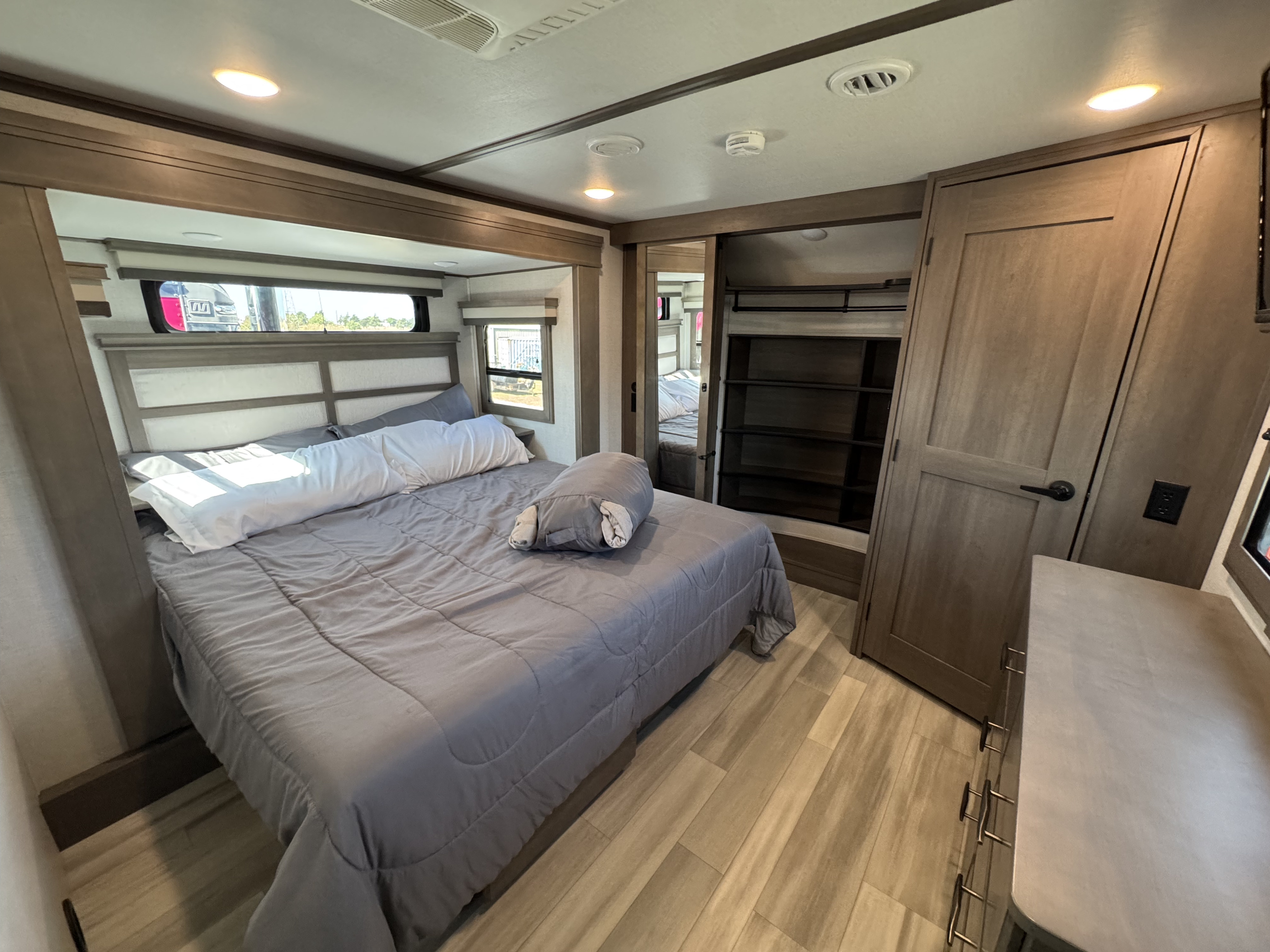 Spacious RV rental bedroom with a comfortable bed, modern wood accents, and built-in storage, perfect for travel.. Grand Design Solitude 2023