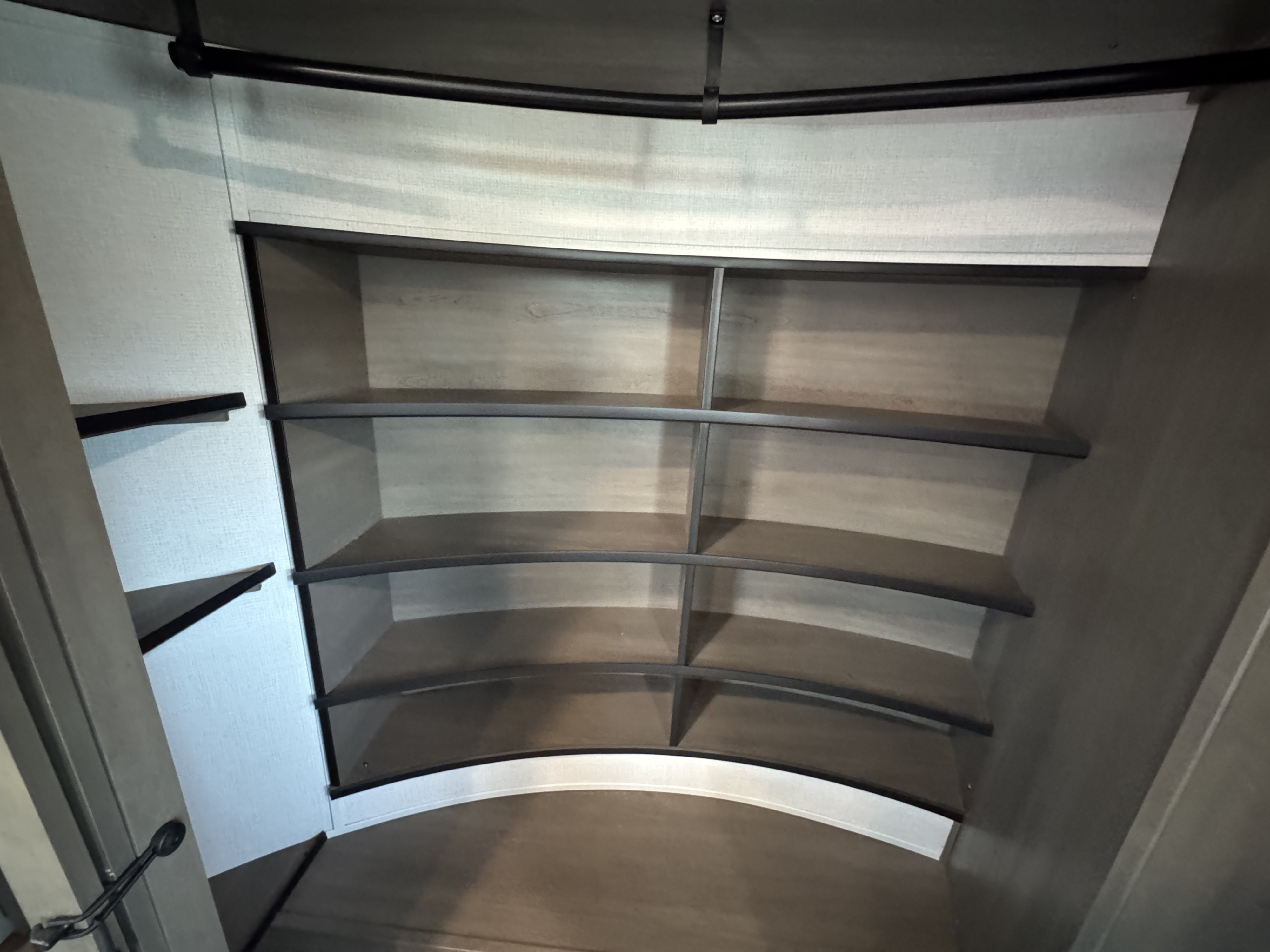 This RV rental closet features curved shelves and a clothing rod, offering practical storage for your travel essentials.. Grand Design Solitude 2023