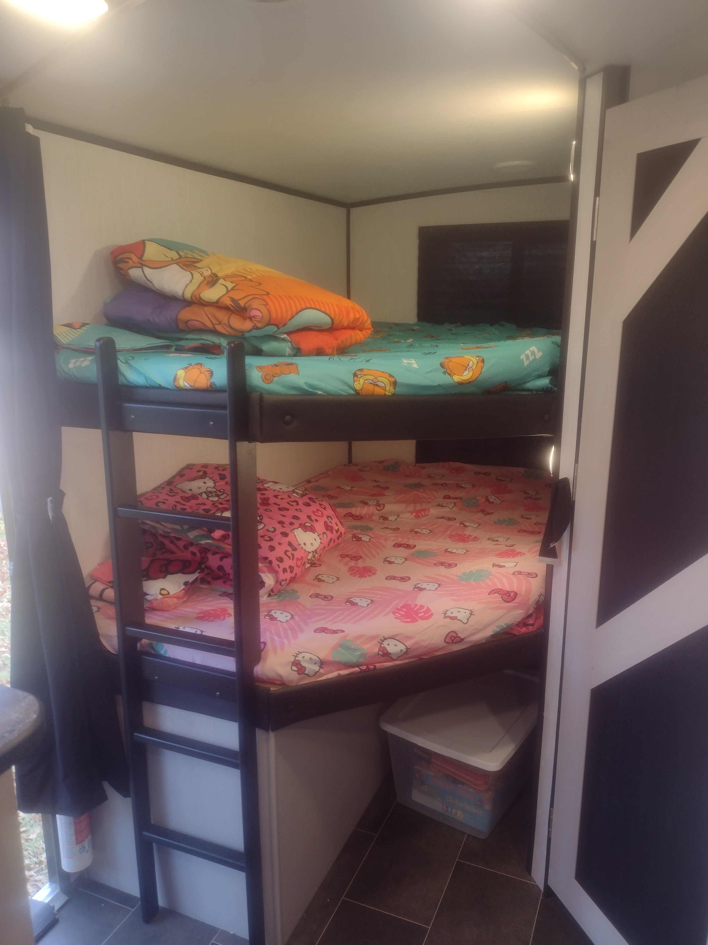 Cozy RV rental bunk beds with colorful Hello Kitty and Garfield bedding, perfect for kids in a compact camper space.. Heartland RVs Mallard 2022
