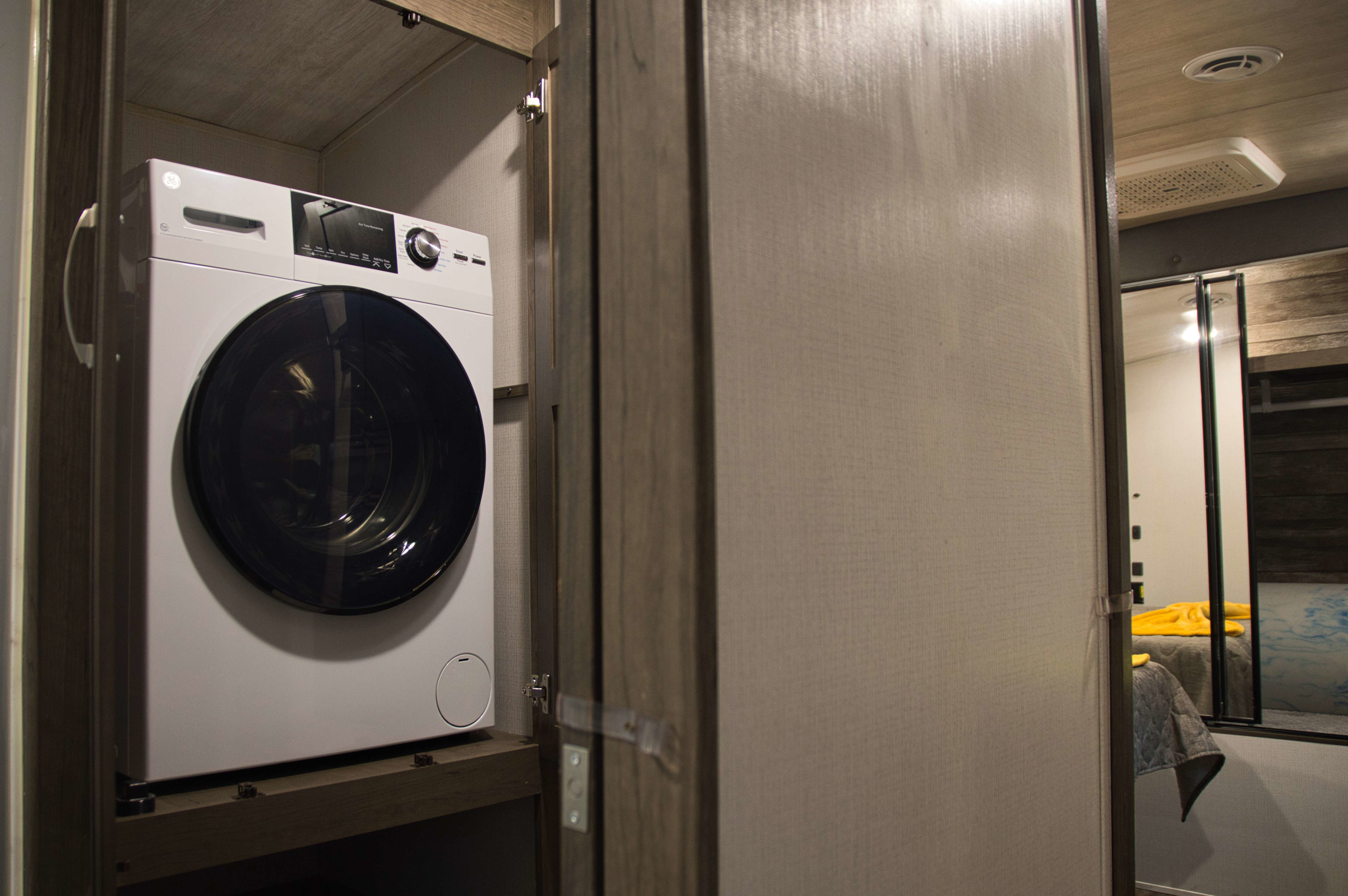 Inside this RV rental, find a compact GE washer/dryer unit for convenient laundry, tucked within a cabinet.. Keystone RV Cougar 2022