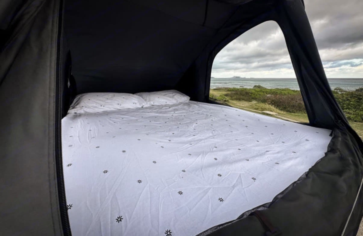 Comfortable bed inside a rooftop tent RV rental with an amazing ocean view for your next outdoor adventure.. Ford Econolline 250s 2005