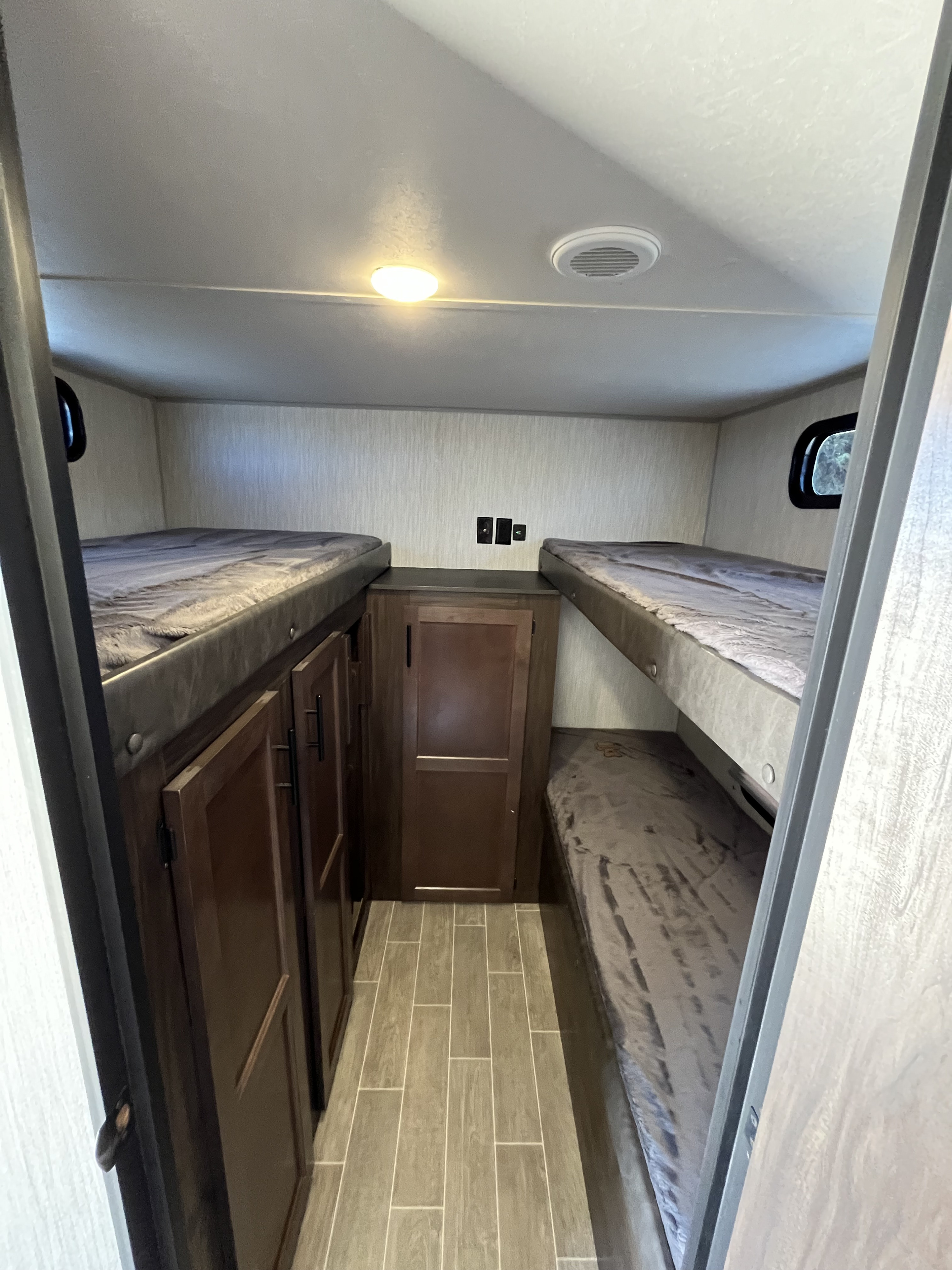 RV rental bunkhouse with four bunk beds (two on each side), central storage cabinets, and wood-look tile flooring.. Forest River Cherokee Grey Wolf 2021