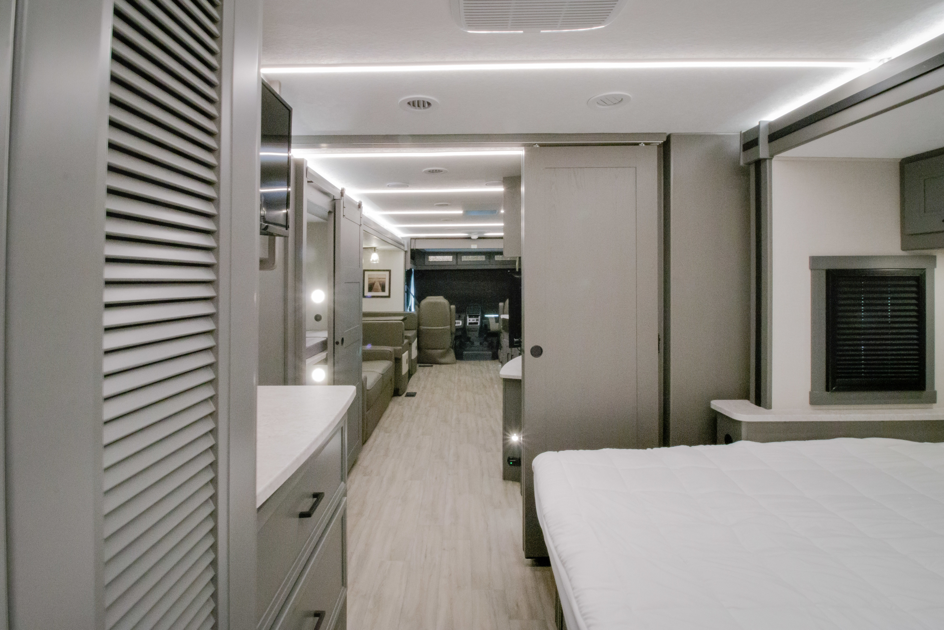 Step inside this modern RV rental! The sleek grey interior features a cozy bedroom, a well-lit living area, and the driver's cockpit.. Forest River Coachmen Mirada 2026
