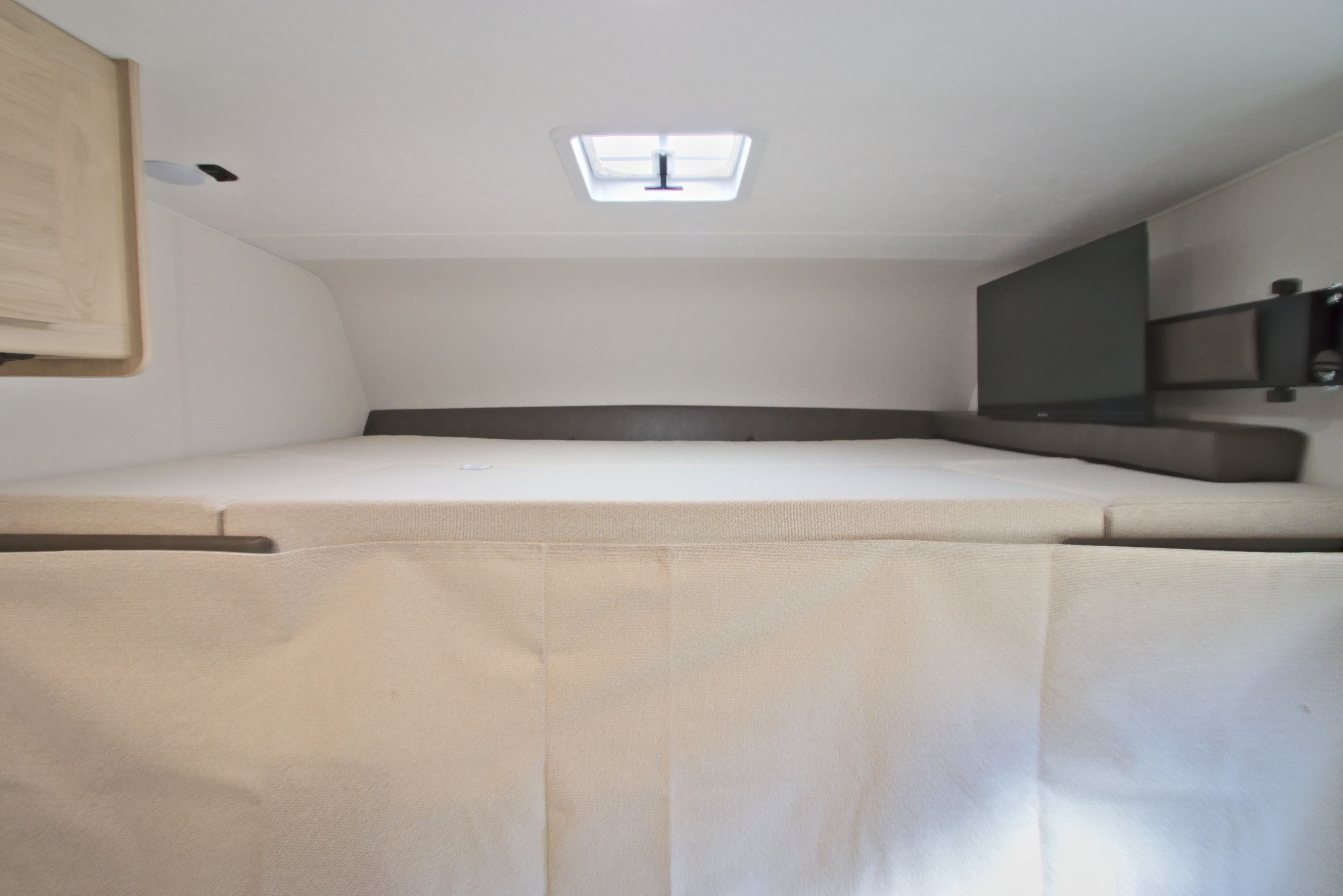 Comfortable RV rental sleeping area featuring a bed, mounted TV, soundbar, and skylight overhead.. Forest River Coachmen Leprechaun 2026