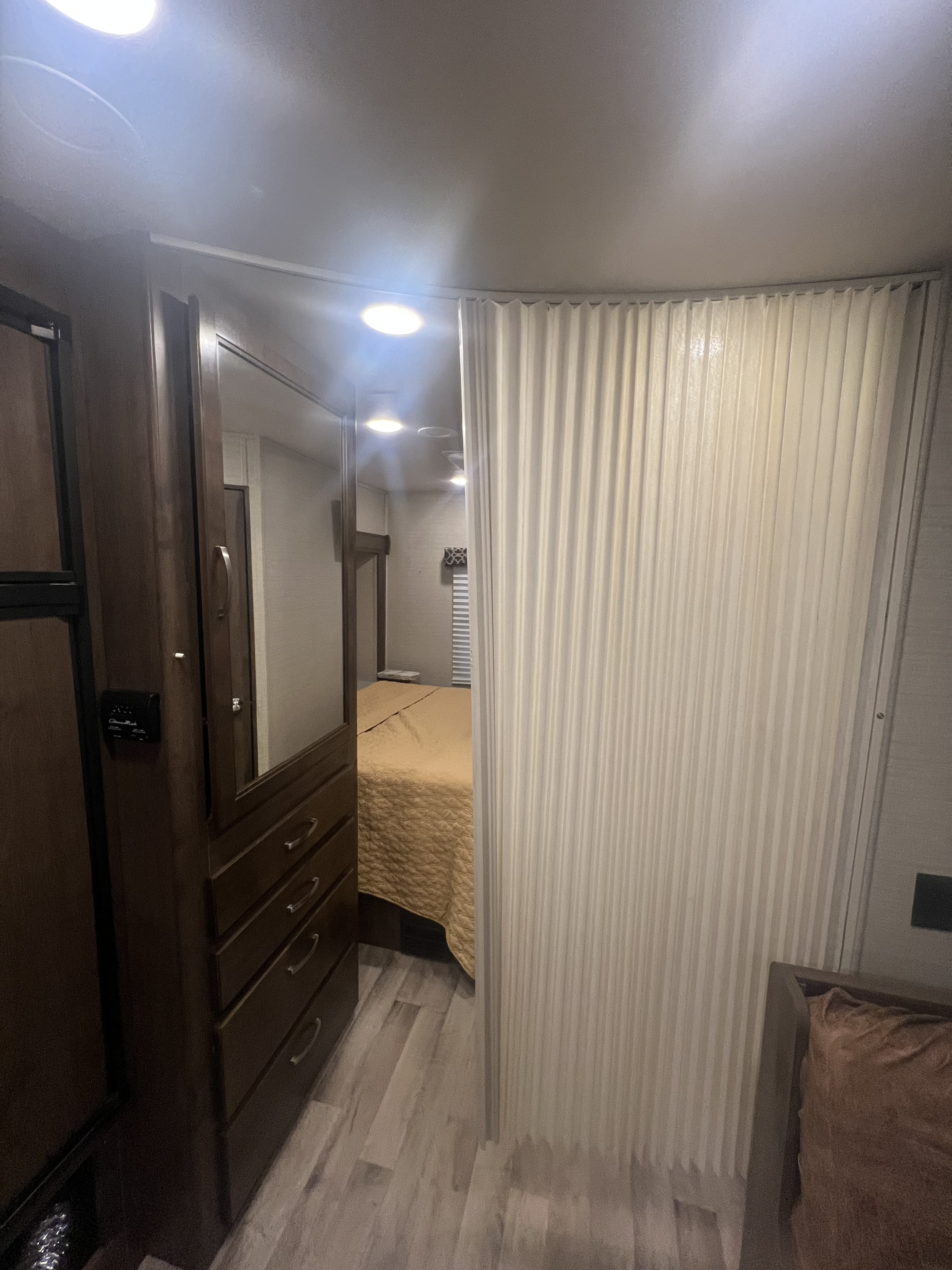 Inside an RV rental: a compact bedroom with a comfy bed, mirrored wardrobe, and privacy curtain.. Jayco Redhawk 2019