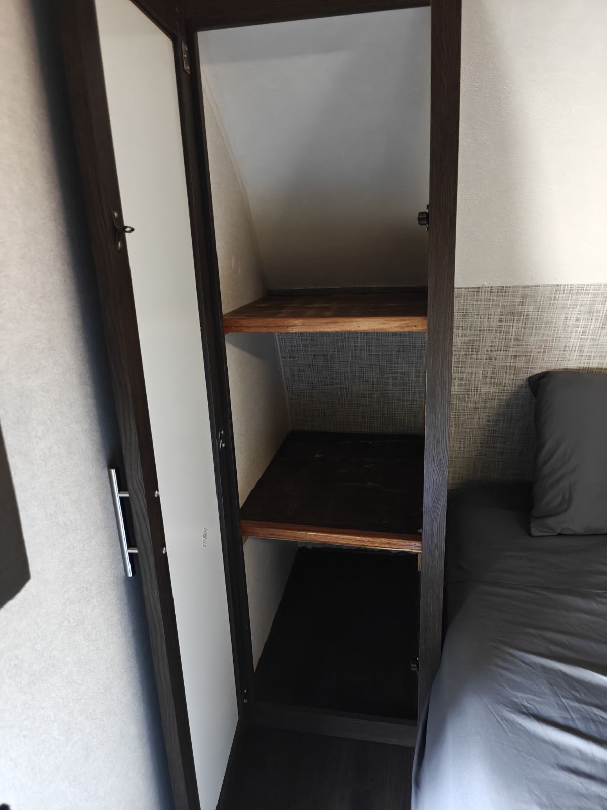 RV rental: compact bedroom storage featuring an open closet with two wooden shelves next to a gray bed.. Salem 26DBUD 2020