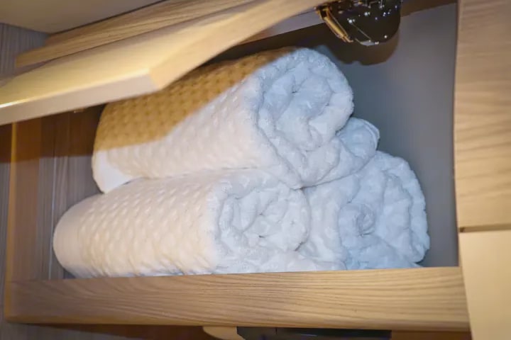 Cozy rolled towels & plush blankets neatly stored in an RV rental closet, ready for your trip.. Thor Sequence 2024