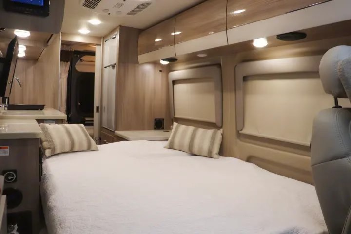 Spacious RV rental interior with a comfy bed, kitchen counter, storage, and light wood finishes. Bright & practical.. Thor Sequence 2024