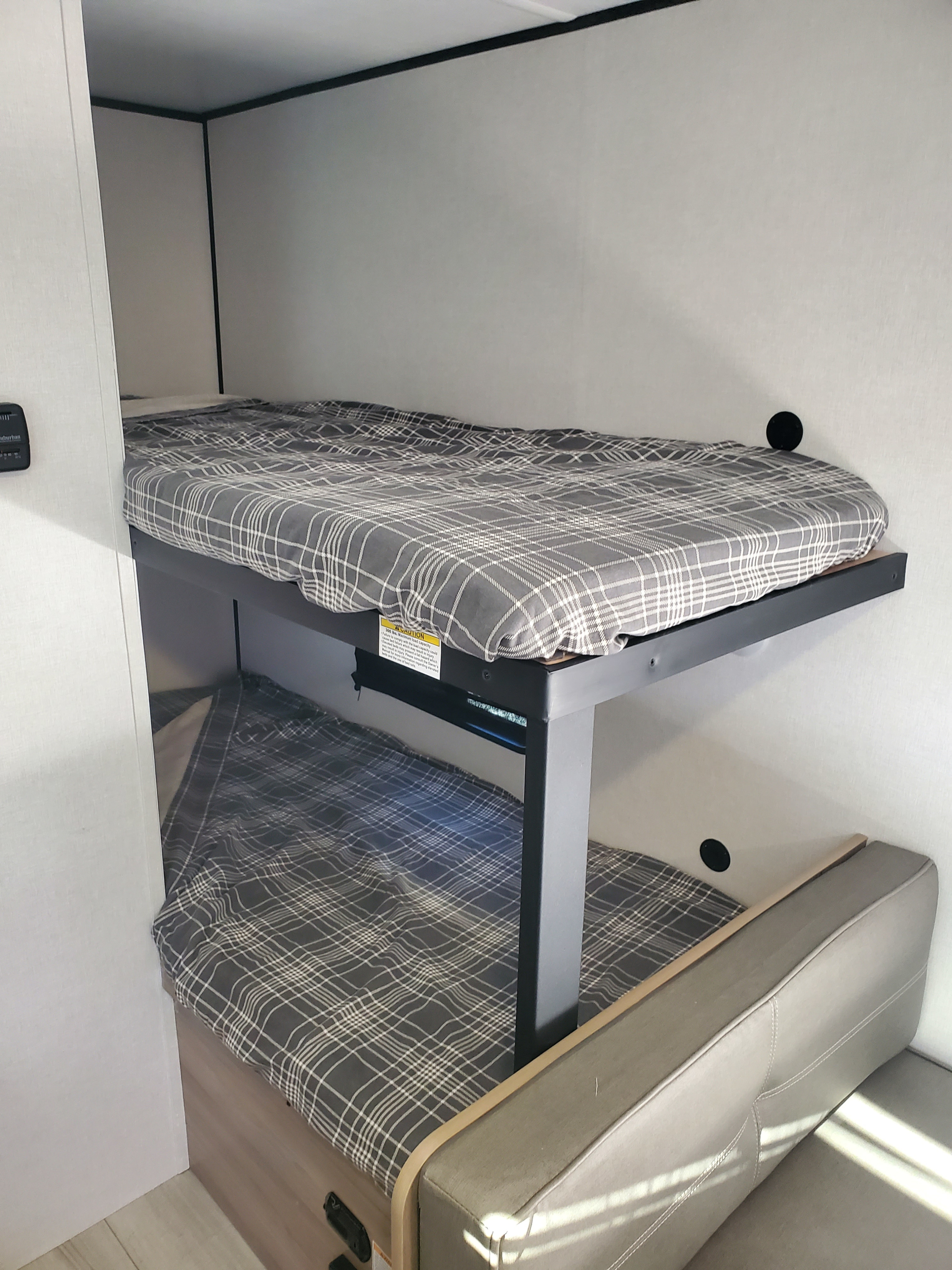 RV rental bunk beds: a cozy, space-saving sleeping area with gray plaid bedding, ideal for family travel.. Keystone Coleman 2026