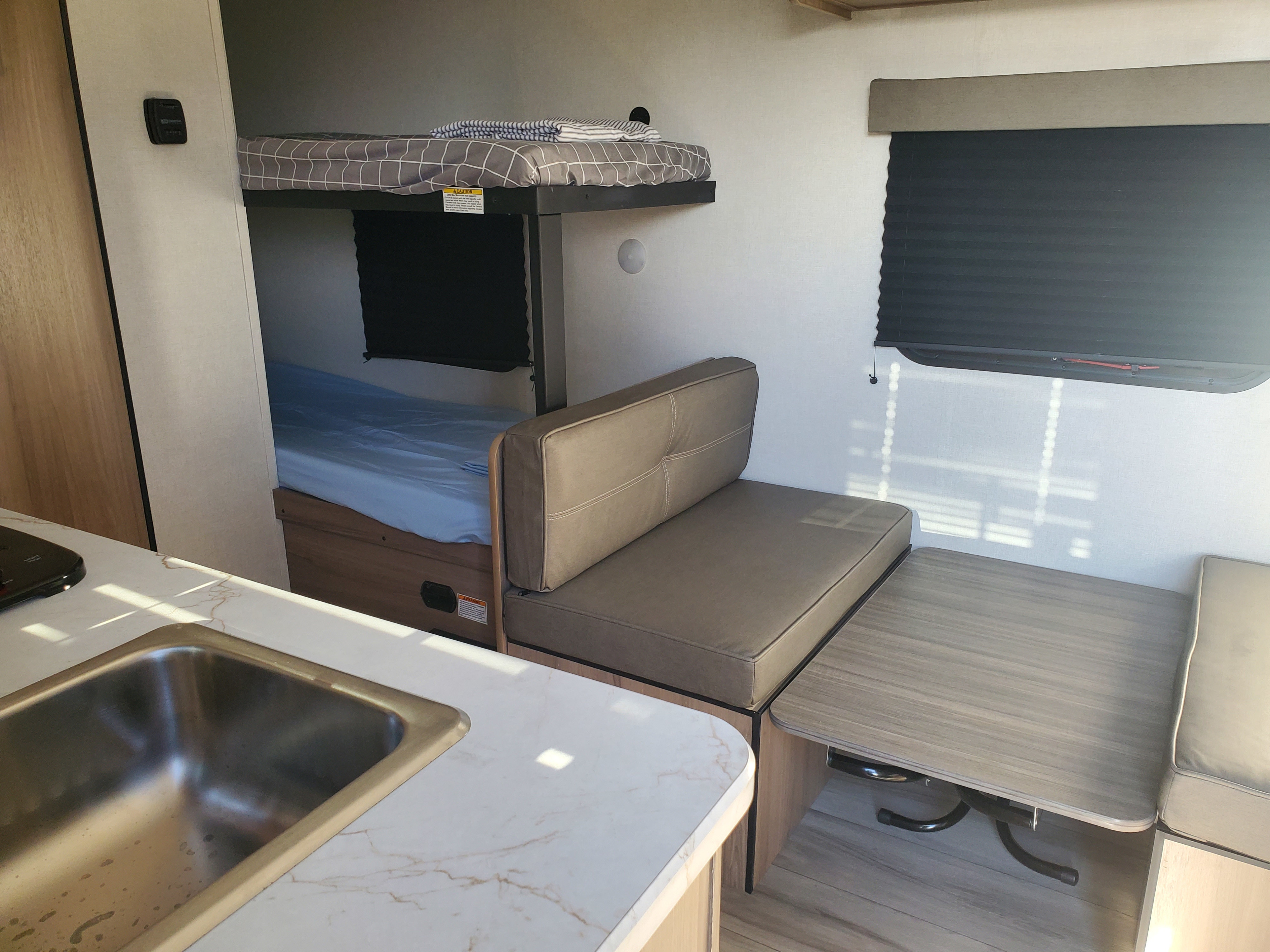 Cozy RV rental interior with bunk beds, dinette, and kitchen sink, offering comfortable living space for campers.. Keystone Coleman 2026