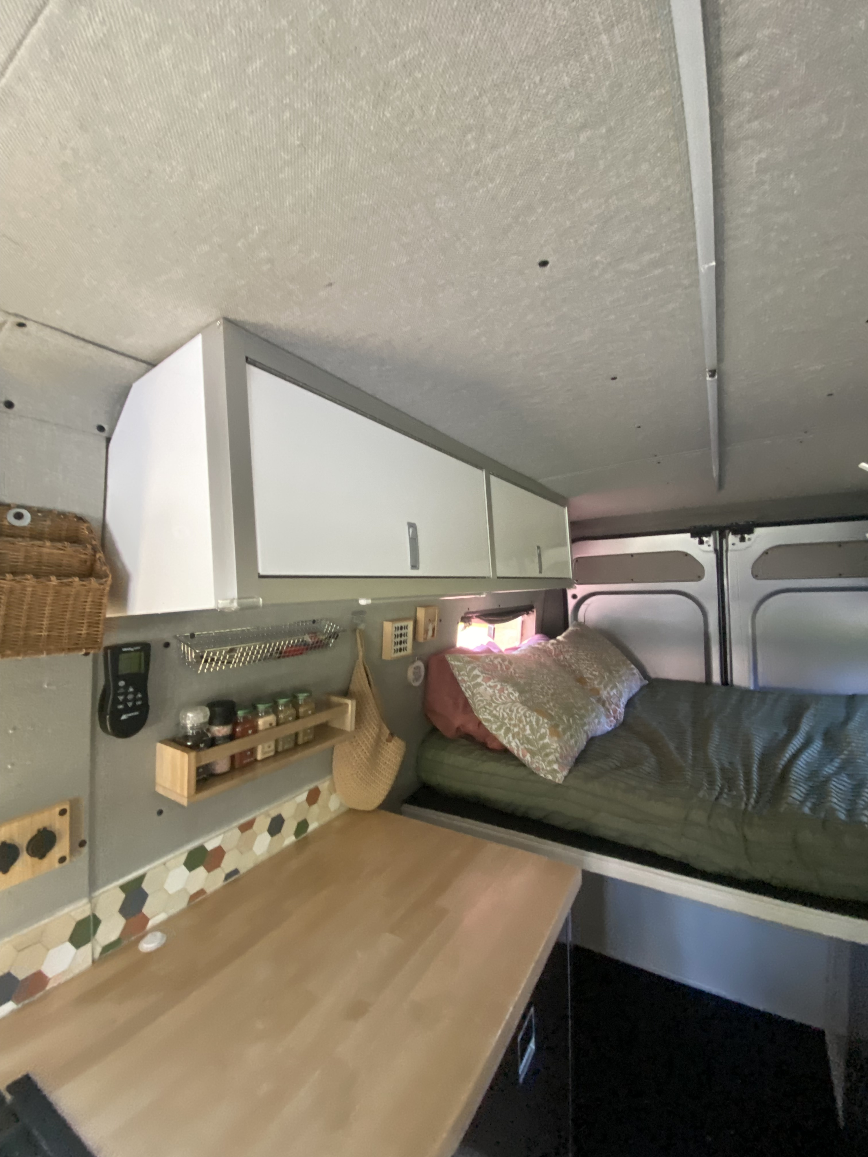 Cozy RV rental campervan interior: features overhead storage, a comfortable bed, and a functional kitchen counter.. Dodge Promaster 3500 2017
