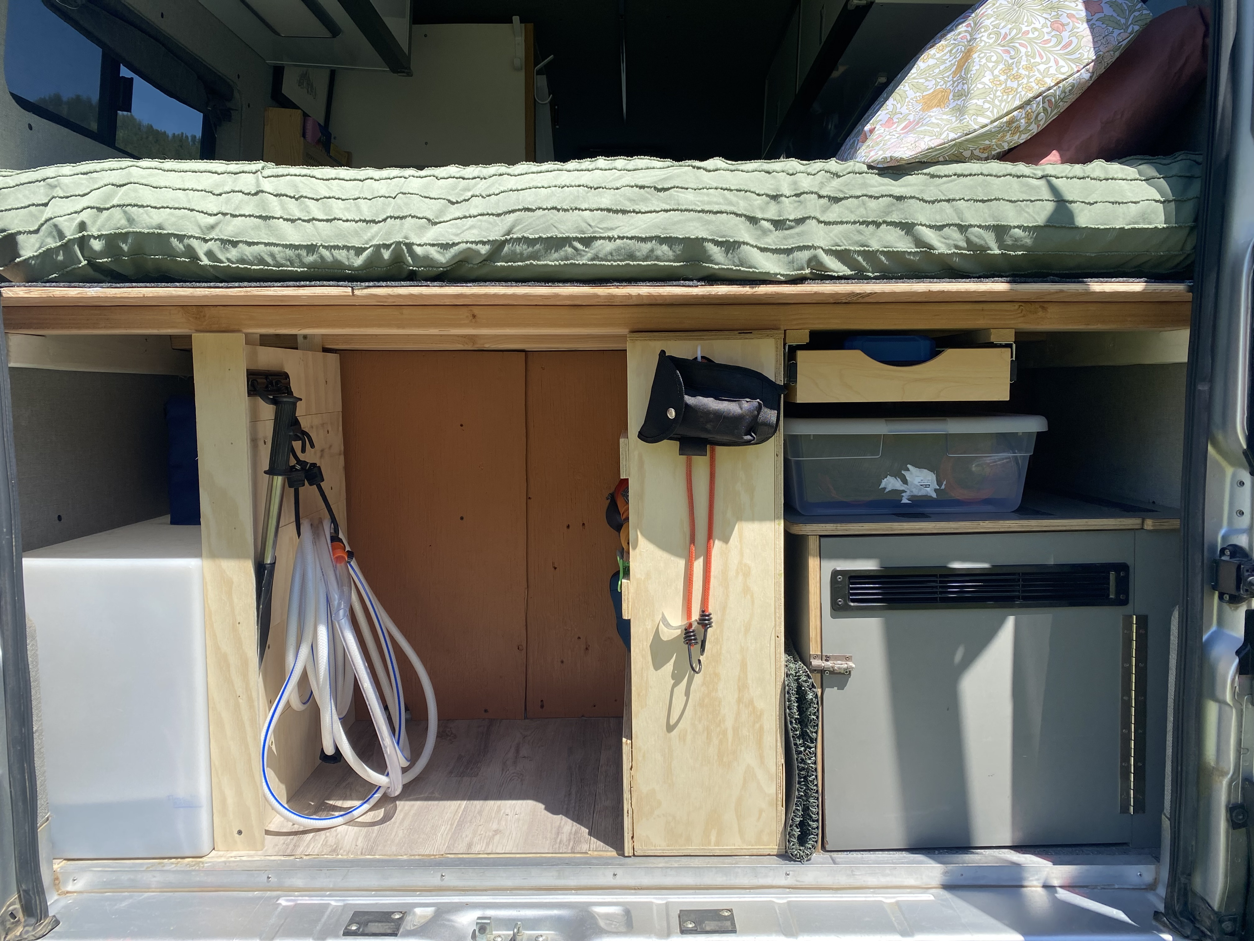 Inside an RV rental: Organized storage under the bed features a water tank, coiled hose, camping gear, and portable fridge.. Dodge Promaster 3500 2017