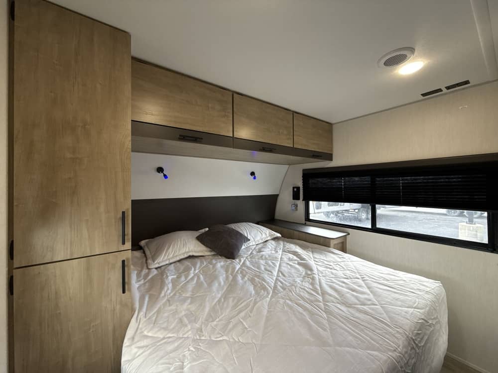 Modern RV rental bedroom with a comfortable bed, ample wood storage, and large window for scenic views.. Forest River Campsite Reserve 26CJ 2026