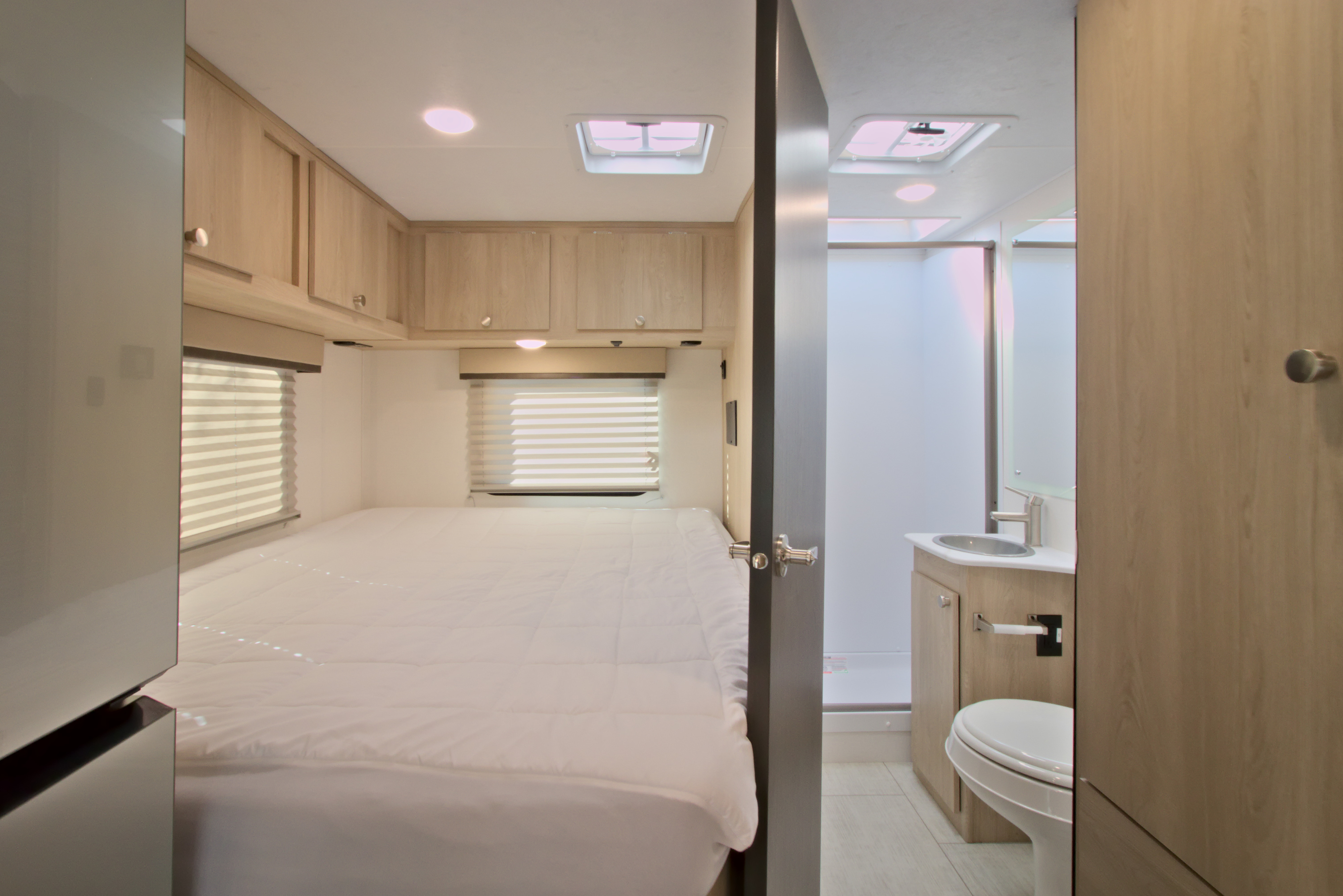 Modern rv rental interior: comfortable bedroom with bed, overhead storage, and a well-equipped bathroom with shower, sink, toilet.. Forest River Coachmen Leprechaun SS 2026