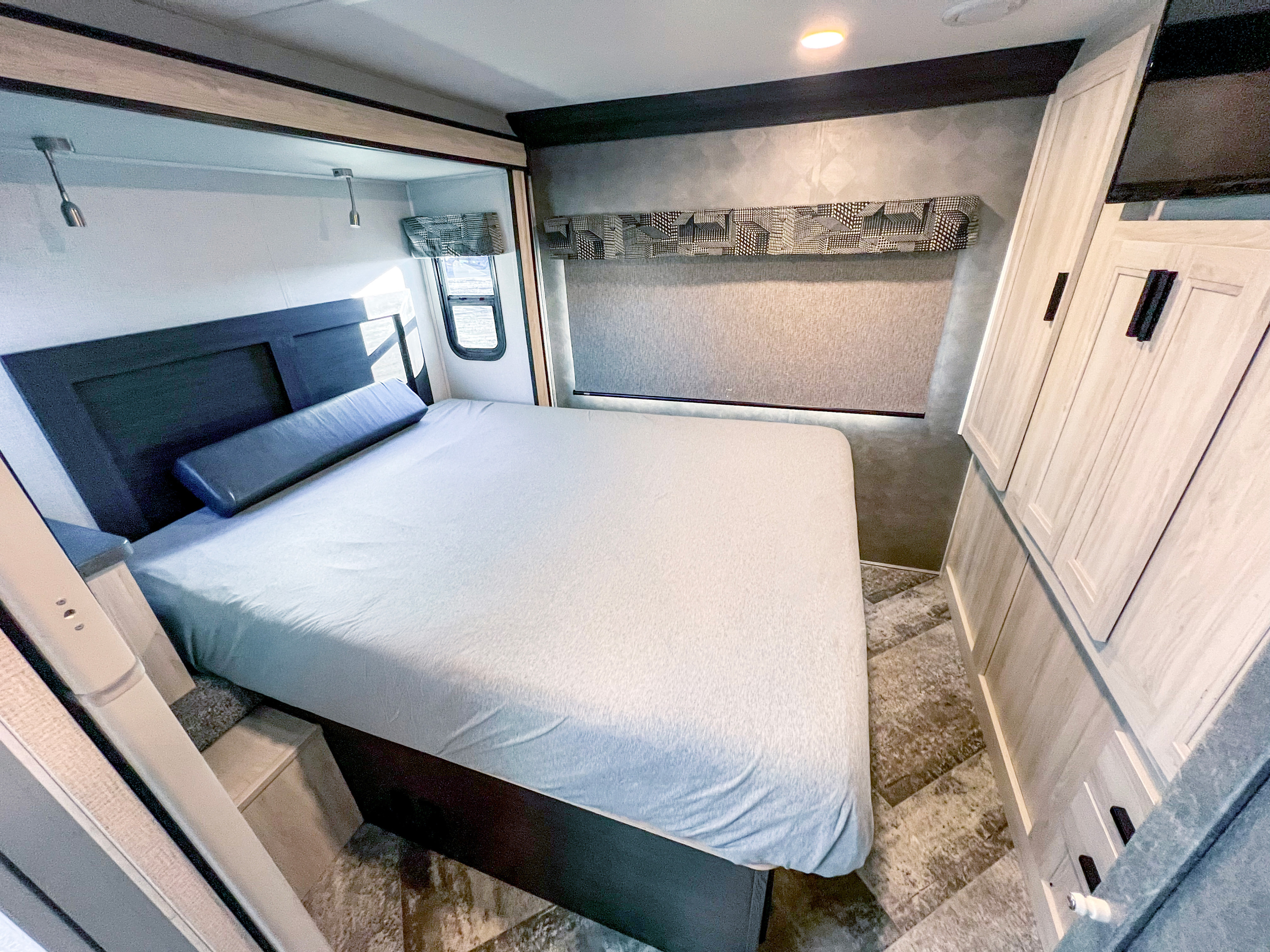 Modern RV rental bedroom features a comfortable bed, stylish headboard, reading lights, and built-in storage.. Forest River sunseeker 2021
