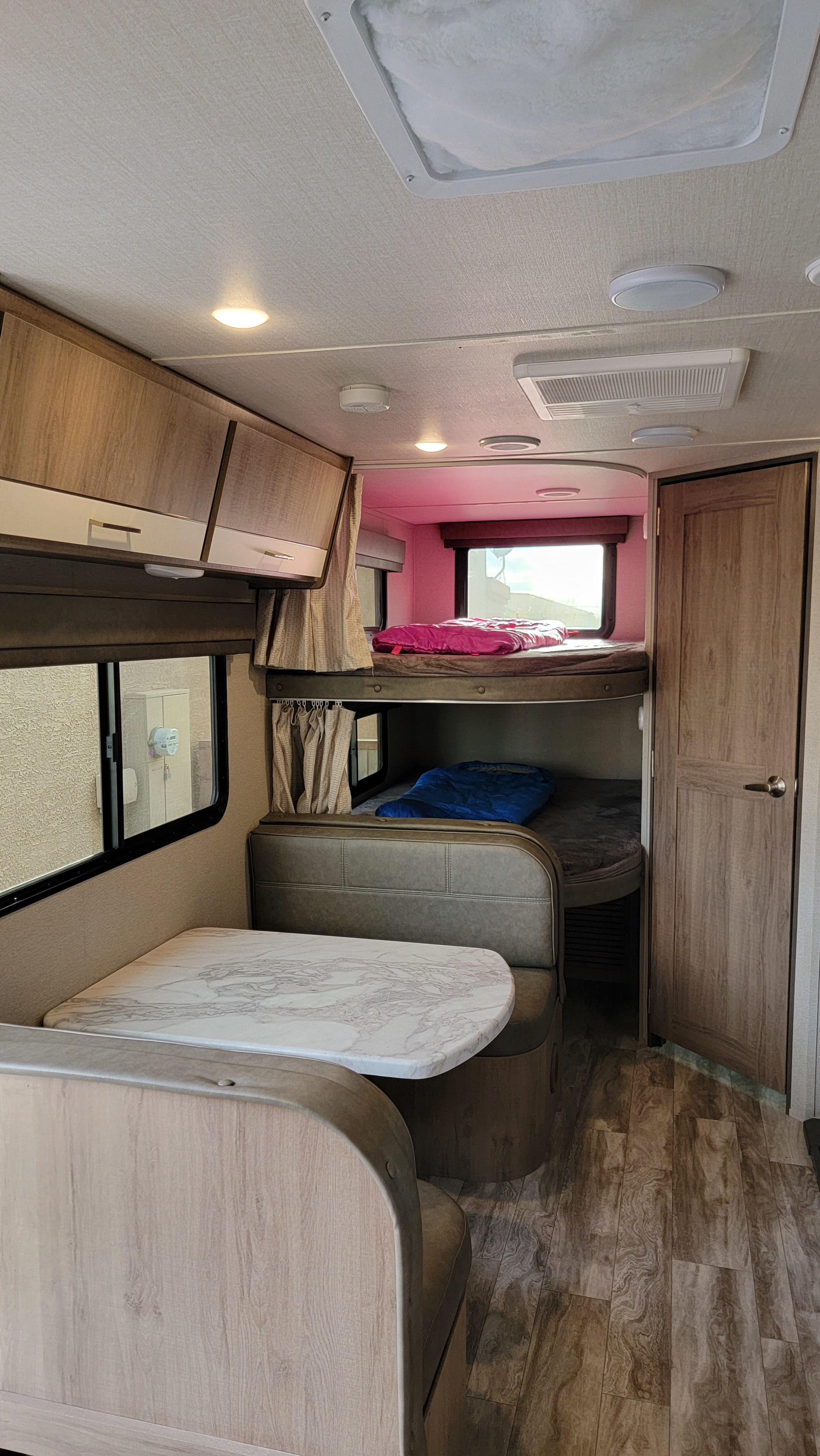 RV rental interior: cozy dinette, bunk beds with pink & blue bedding, ample storage, and ceiling fixtures.. Grand Design Imagine XLS 2022
