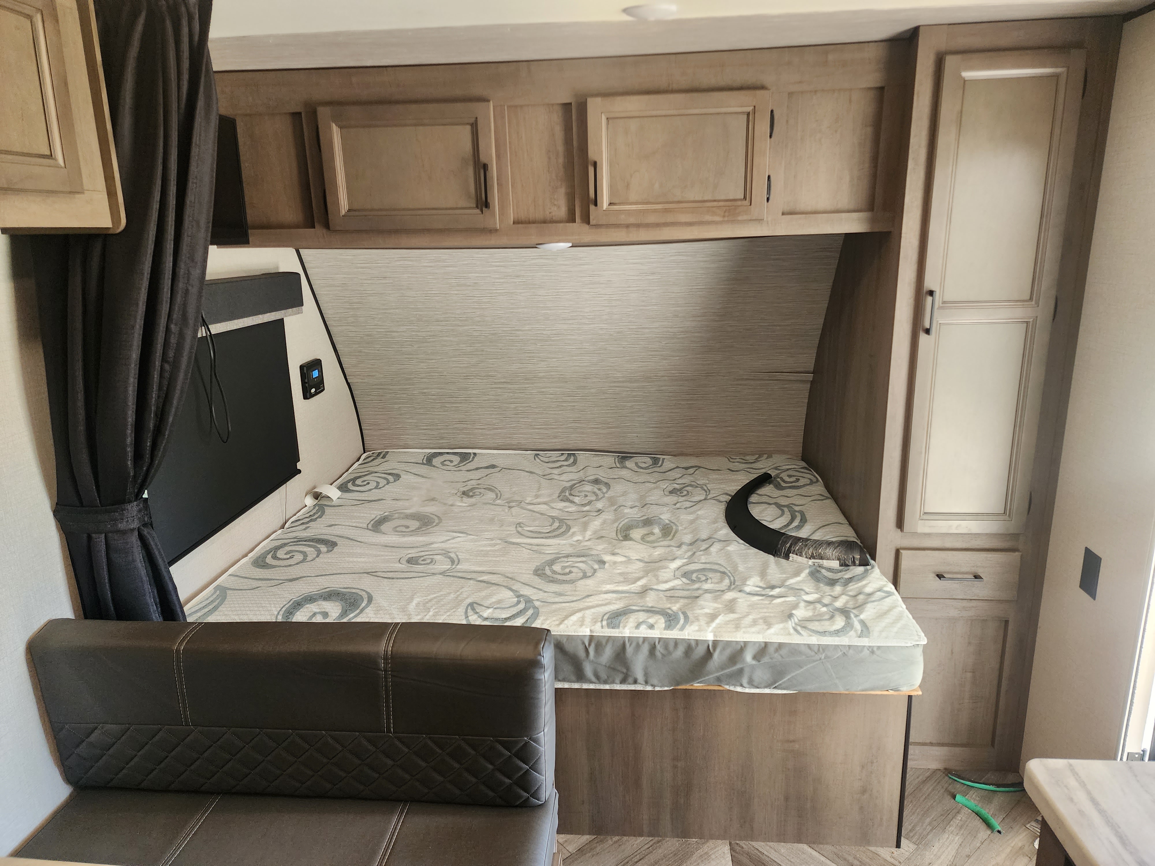 Explore this RV rental's interior: a comfy sleeping area with a bed, overhead cabinets, and seating.. Highland Ridge RV Olympia Sport 2022