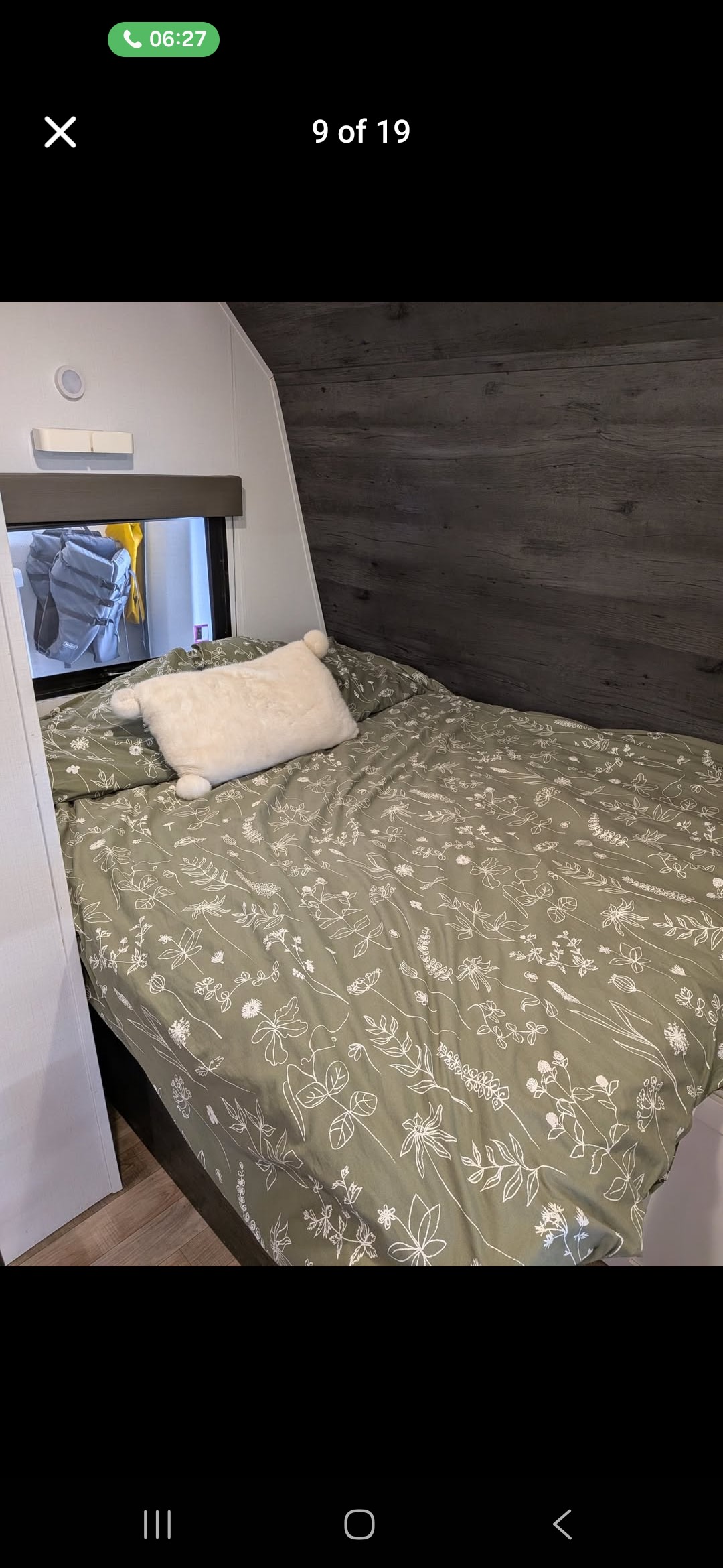 Cozy RV rental bedroom featuring a bed with green floral bedding and a plush white pillow, by a window.. Keystone RV Hideout 2022