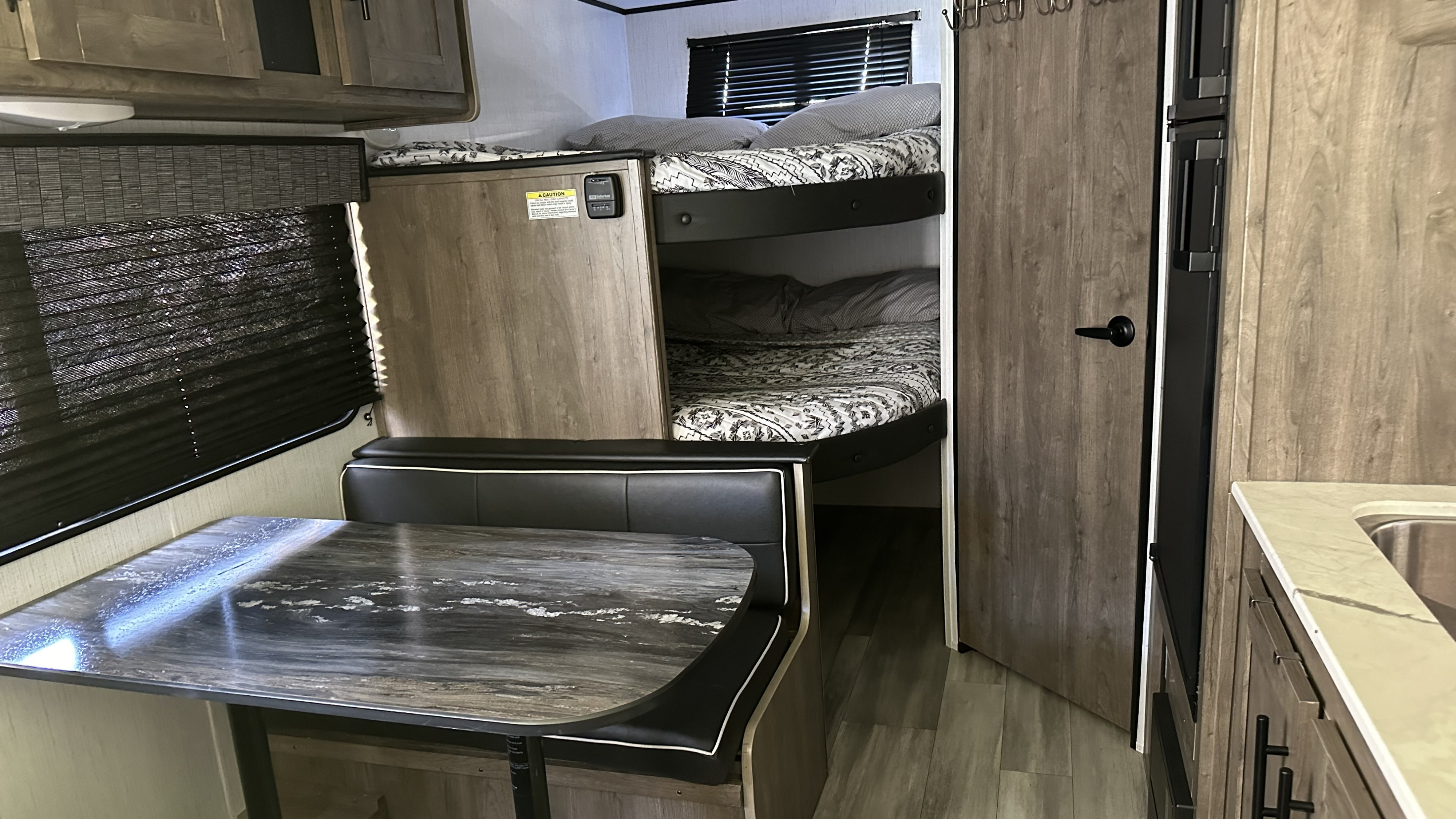 Inside an RV rental: a modern living space featuring a dinette, bunk beds, and compact kitchen for travel comfort.. Heartland RVs Pioneer Trail Blazer 2022