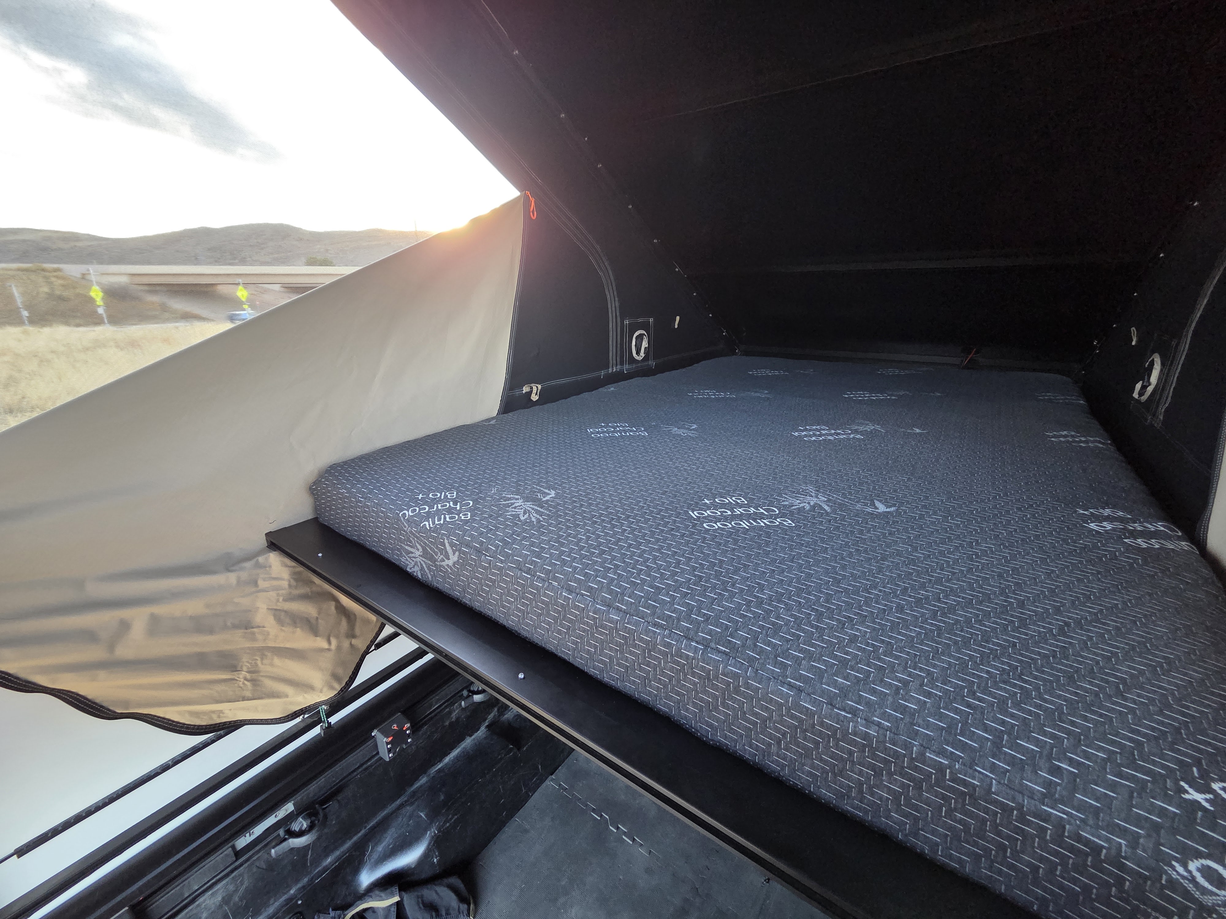 RV rental rooftop tent interior: comfy Bamboo Charcoal mattress, ready for camping trips. Outdoor views visible.. Toyota Tacoma 2018