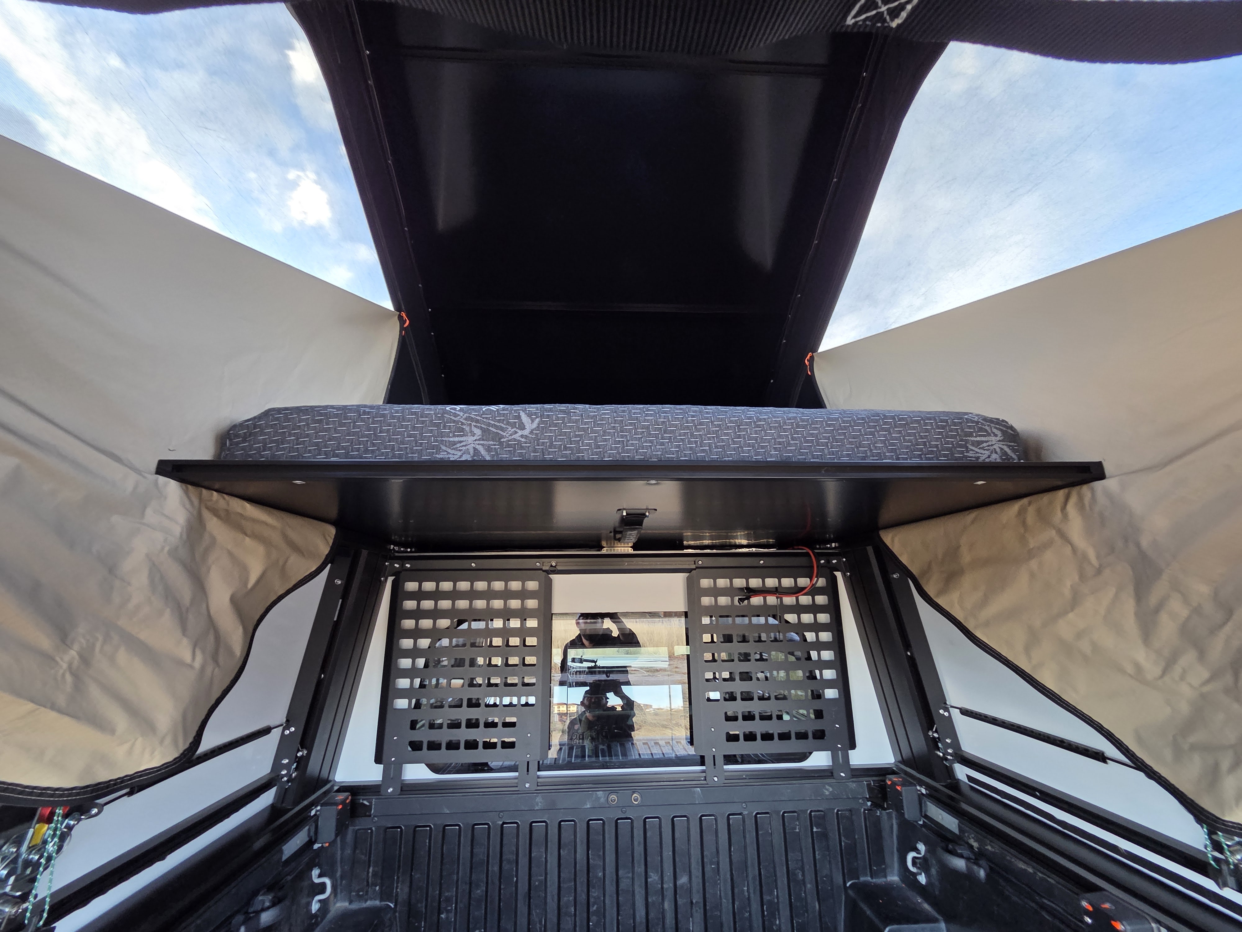Inside a truck bed camper, showing the mattress and cargo grid. Perfect for your next RV rental adventure!. Toyota Tacoma 2018