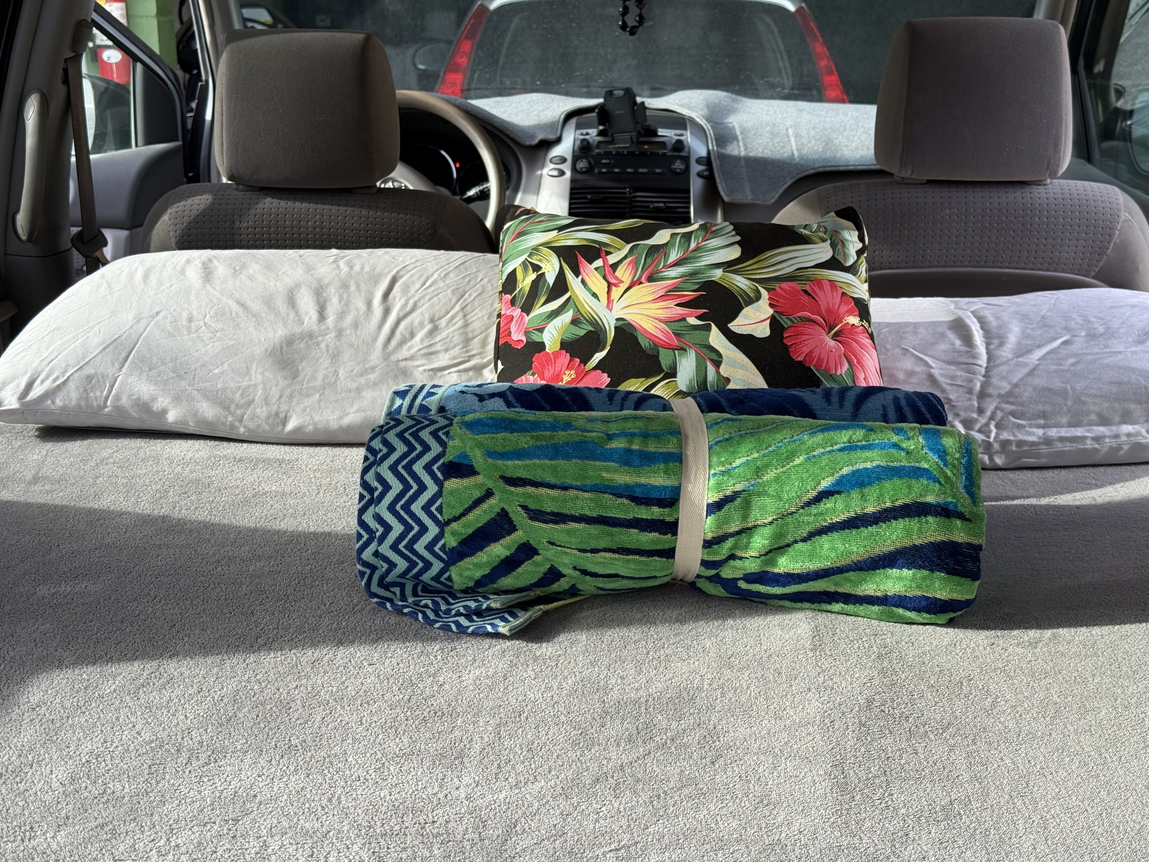 Cozy car setup in an rv rental, with white and floral pillows, plus colorful rolled towels, ready for comfort on a journey.. Toyota Sienna 2006