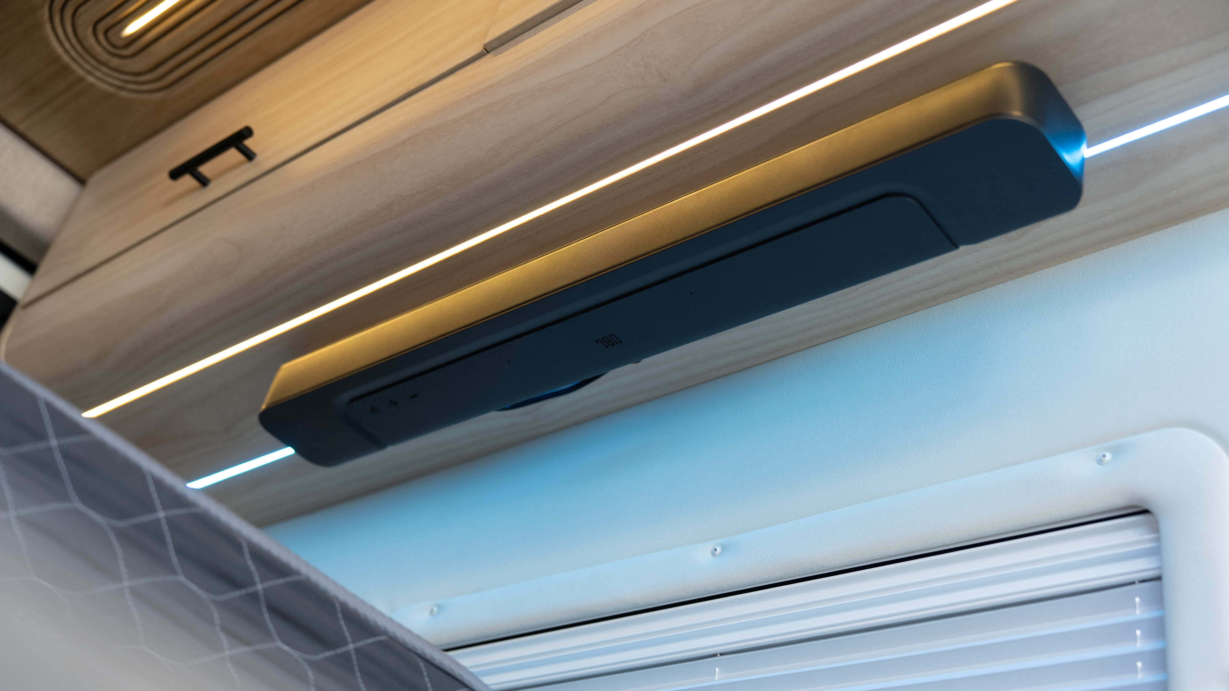 Modern RV rental interior featuring an integrated JBL soundbar, dynamic LED lighting, and wood paneling above window blinds.. Other Mercedes Sprinter 2024