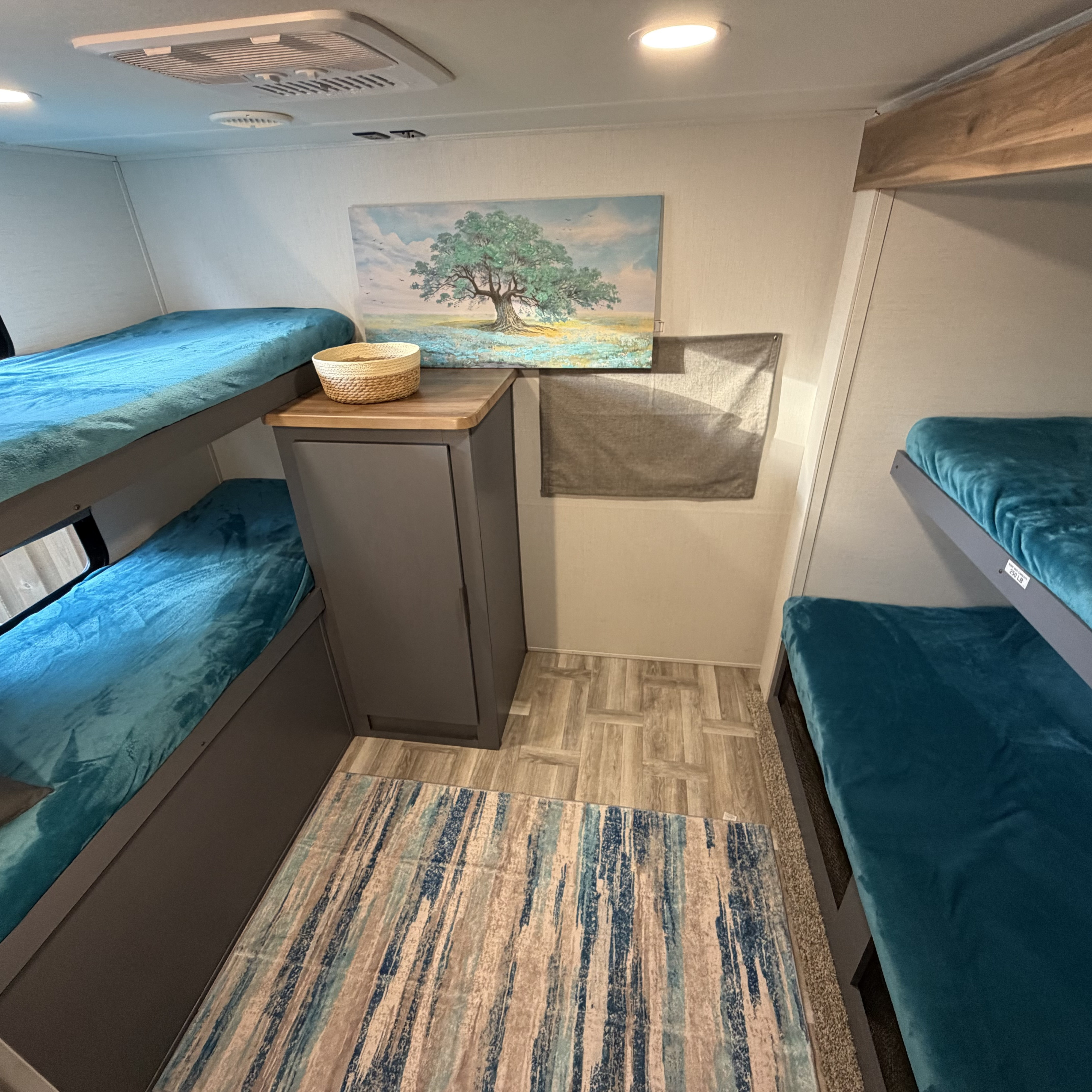 Spacious RV rental bunk room with four teal bunk beds, storage, and art. Ideal for family adventures.. Forest River Tracer Ultra Lite LE 2025