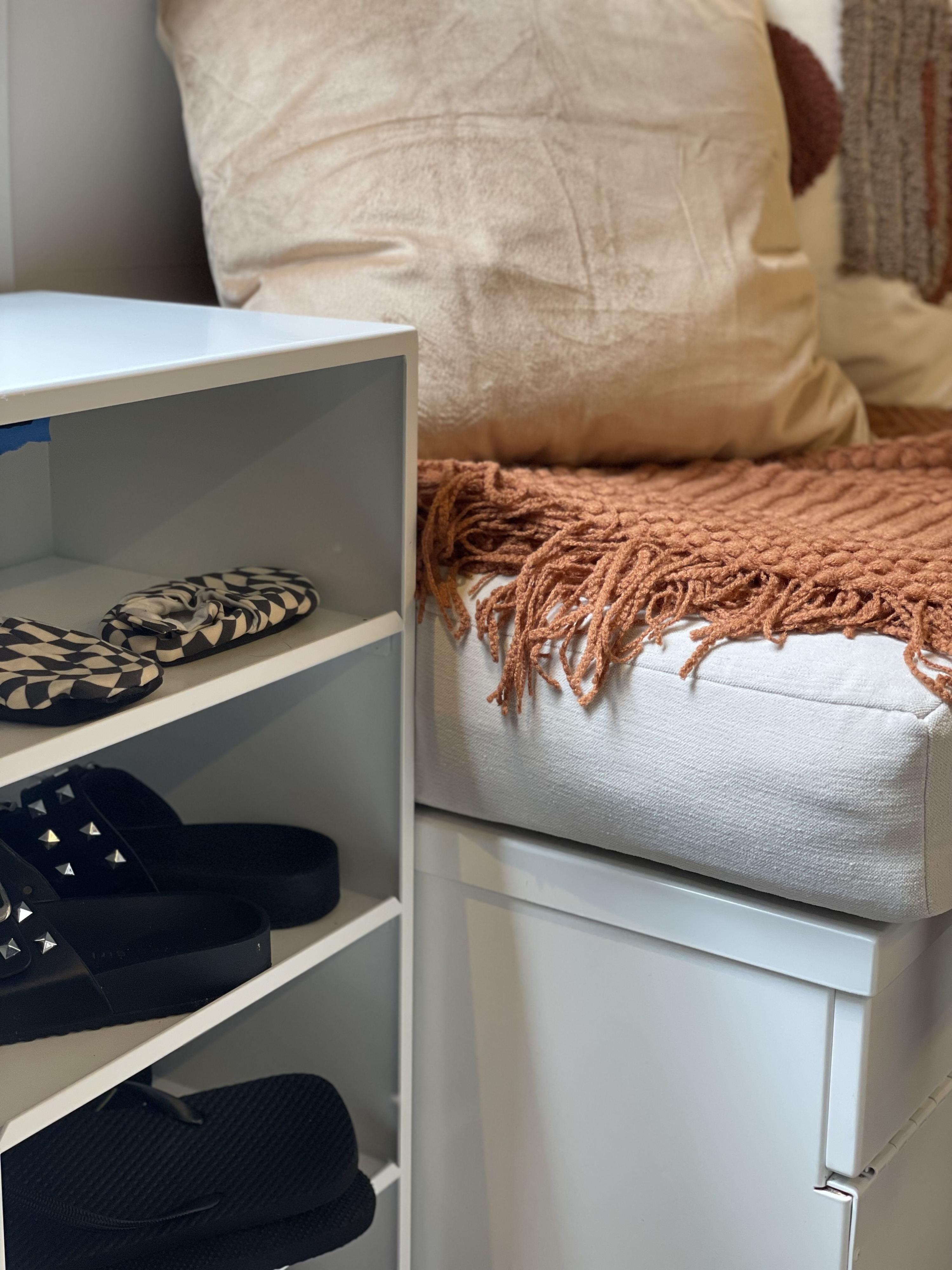 RV rental interior: multi-tier shoe storage & a cozy bench with a soft pillow and textured blanket.. Mercedes-Benz Sprinter 2022