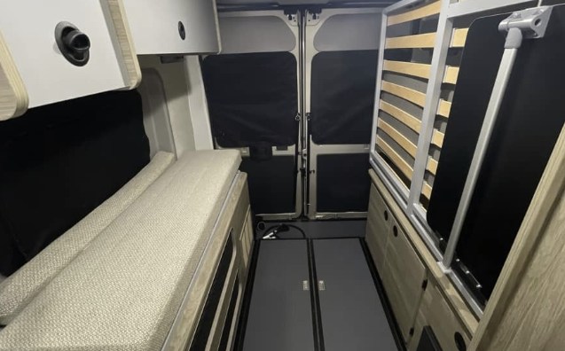 Explore this compact rv rental interior: modular bed, upright slatted frame, and rear privacy screens for versatile travel.. Winnebago Solis 2025