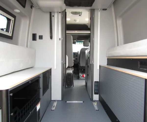 RV rental interior: practical design with gray floor, comfortable bench seating, under-seat storage, leading to the front cabin.. Winnebago Revel 2025