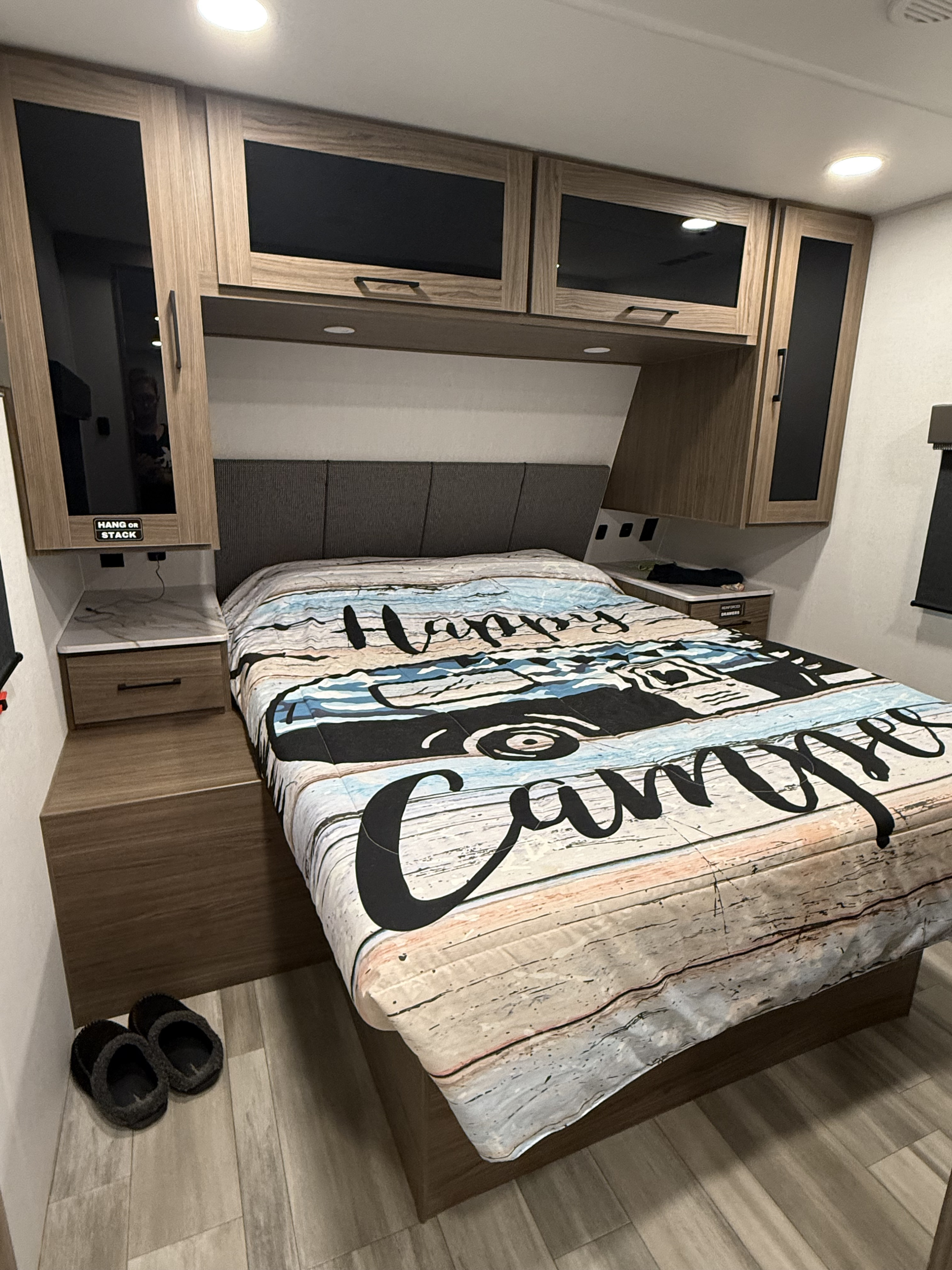 Cozy RV rental bedroom with "Happy Camper" bedding, built-in storage, and convenient nightstands for travel comfort.. Alliance RV Delta Ultra Light 2025