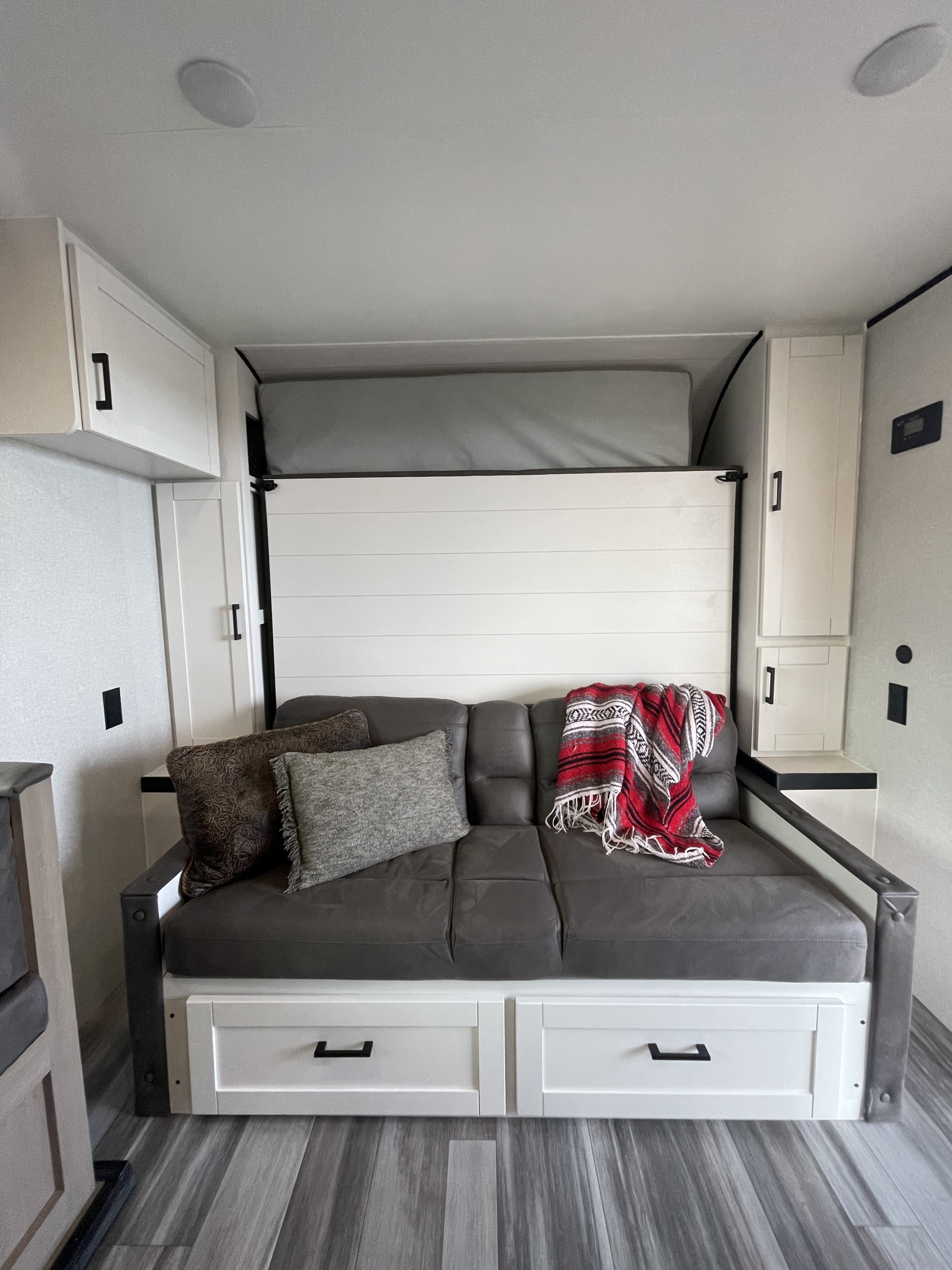 This RV rental features a practical gray sofa that converts to a murphy bed, complete with cozy pillows and a red blanket.. Jayco 197 MBW Baja 2026