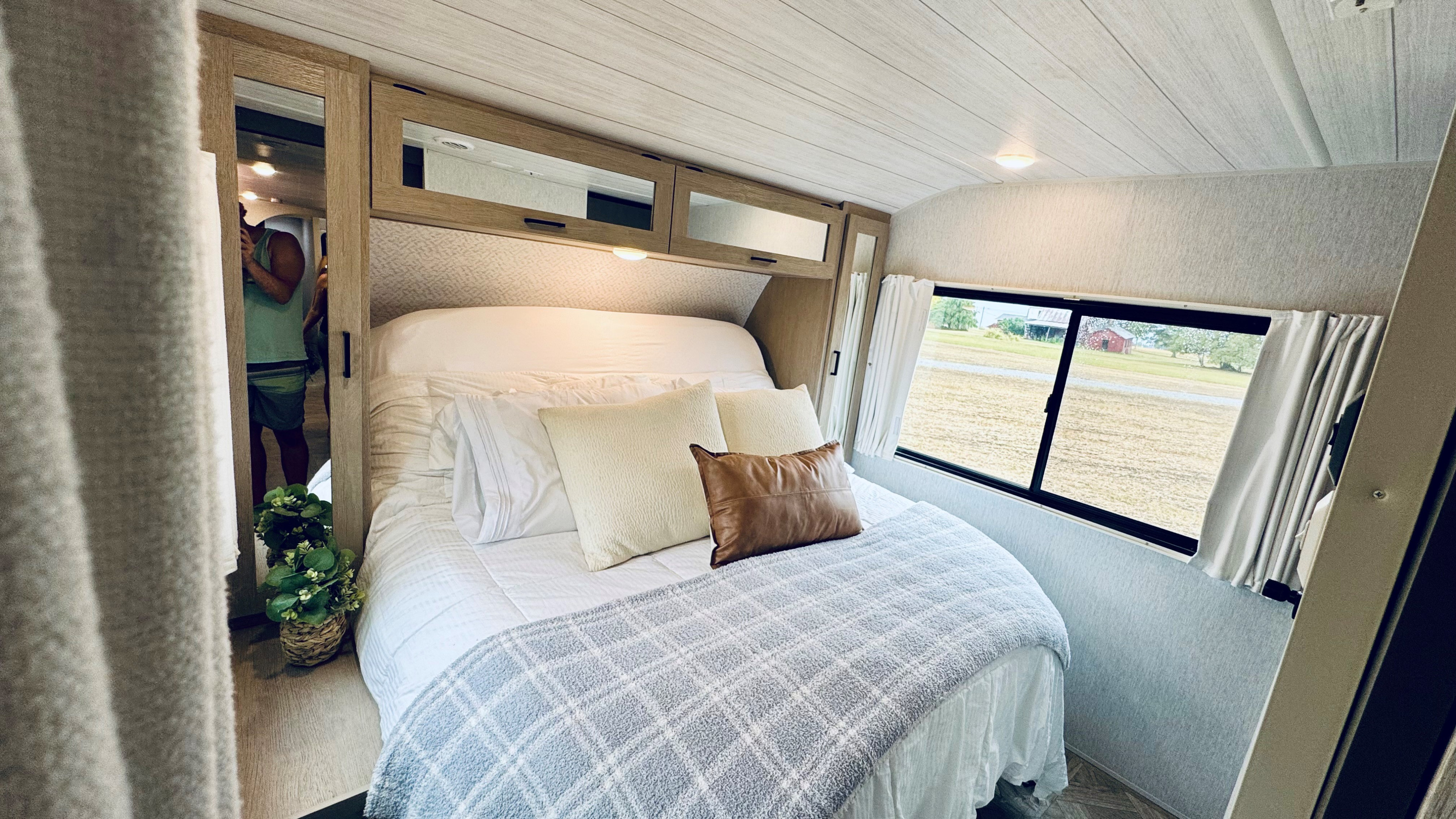 This comfortable rv rental bedroom features a cozy bed, mirrored cabinets, and a scenic window view for your travels.. Forest River Salem Platinum 2024
