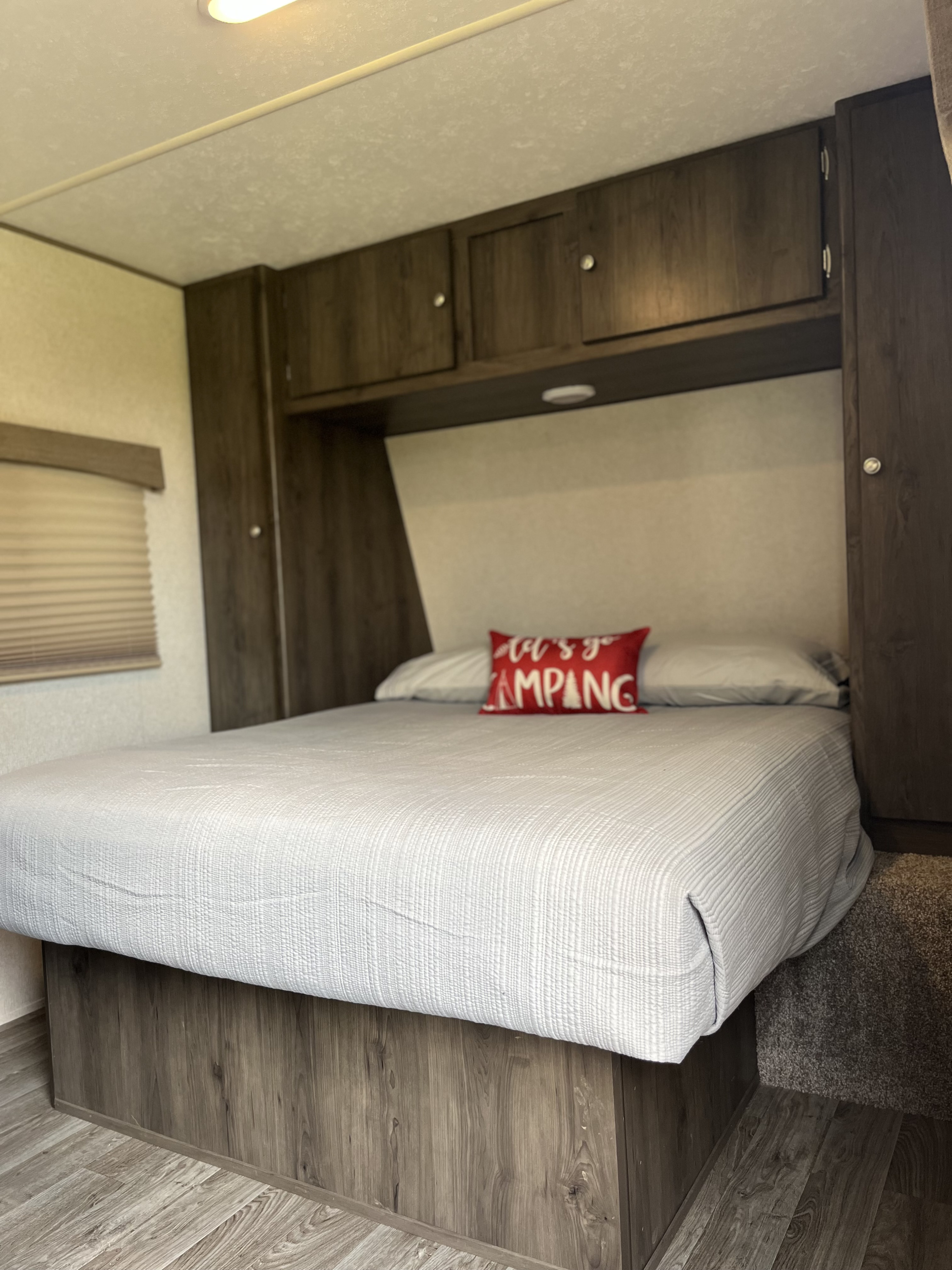 Cozy RV rental bedroom featuring a comfy bed, overhead cabinets, and a "Let's Go Camping" pillow. Perfect for your next adventure!. Coachmen Viking Saga 21SBH 2019