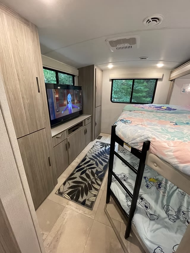 Cozy RV rental interior: Bunk beds, TV with Frozen, and ample storage for a family-friendly trip.. Keystone RV Passport GT Ultra Lite 2024