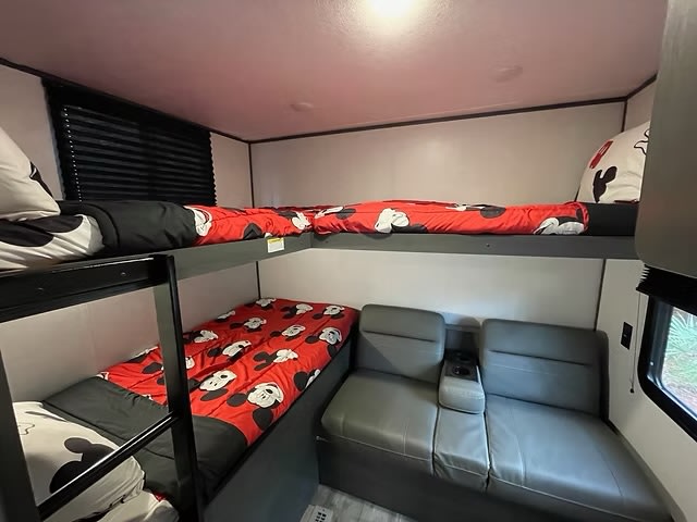 This fun RV rental bunkhouse features Mickey Mouse bedding on four bunks and a cozy sofa, great for family adventures.. Aspen Trail LE 2023