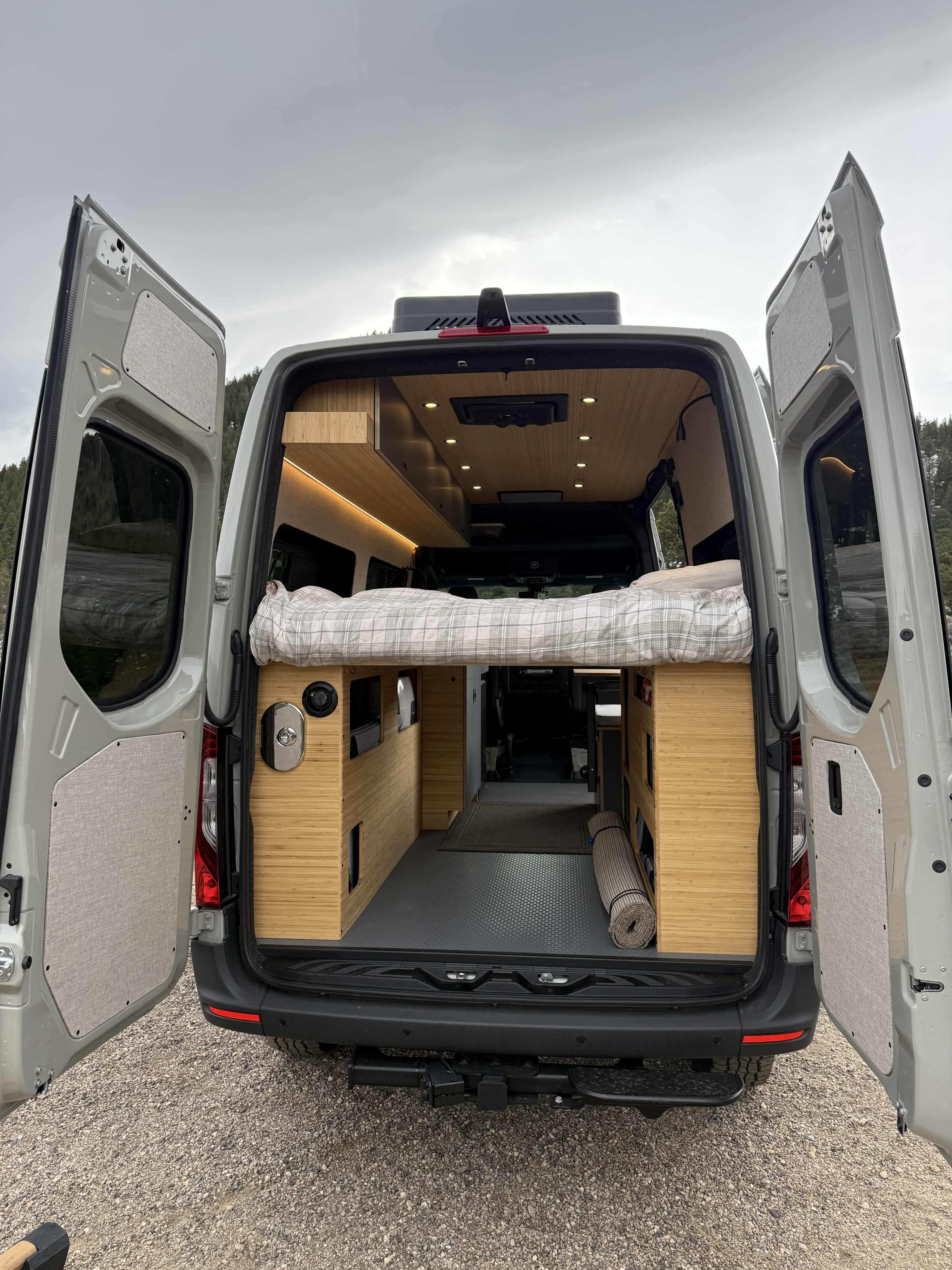 RV rental: Step inside this modern camper van's rear, revealing a cozy bed, wooden interior, and smart storage for travel.. Mercedes-Benz Sprinter 2026