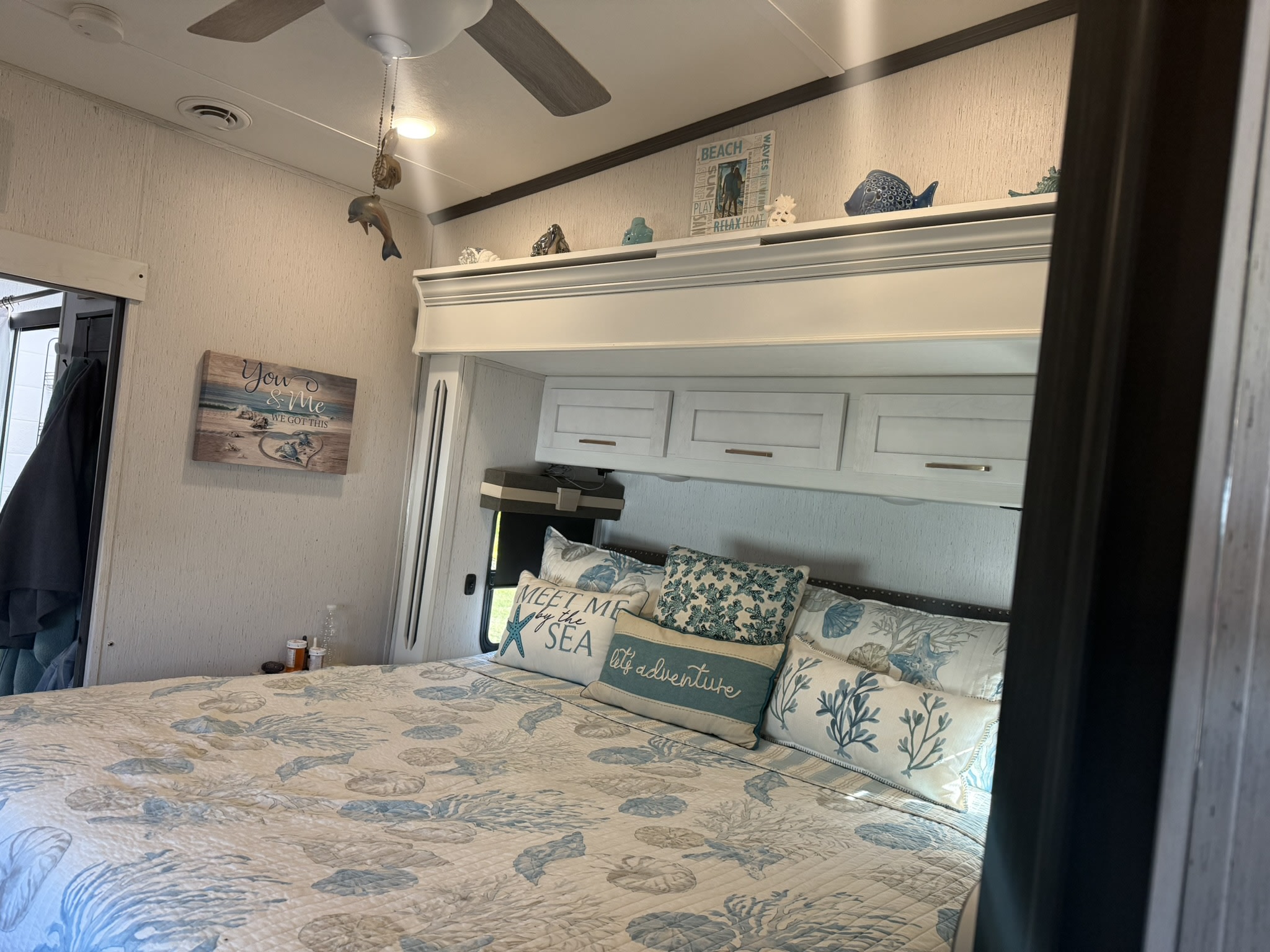 Cozy rv rental bedroom featuring beach-themed decor, "Meet Me by the Sea" pillows, and a cheerful "You & Me" sign.. Astoria Platinum 2024