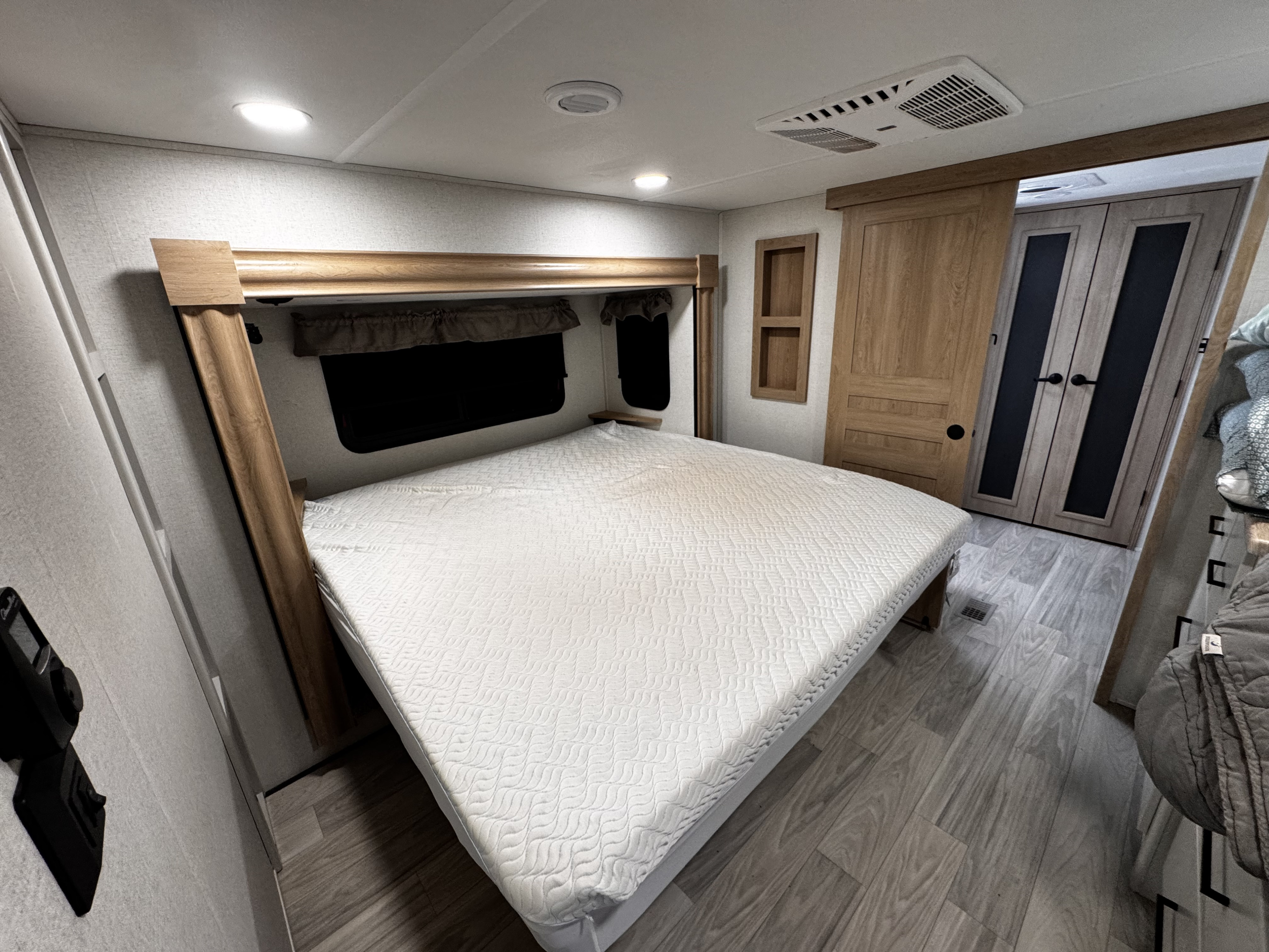 RV rental bedroom interior featuring a comfortable bed with wood accents and ceiling amenities, ready for a cozy stay.. Forest River Sandpiper 2025
