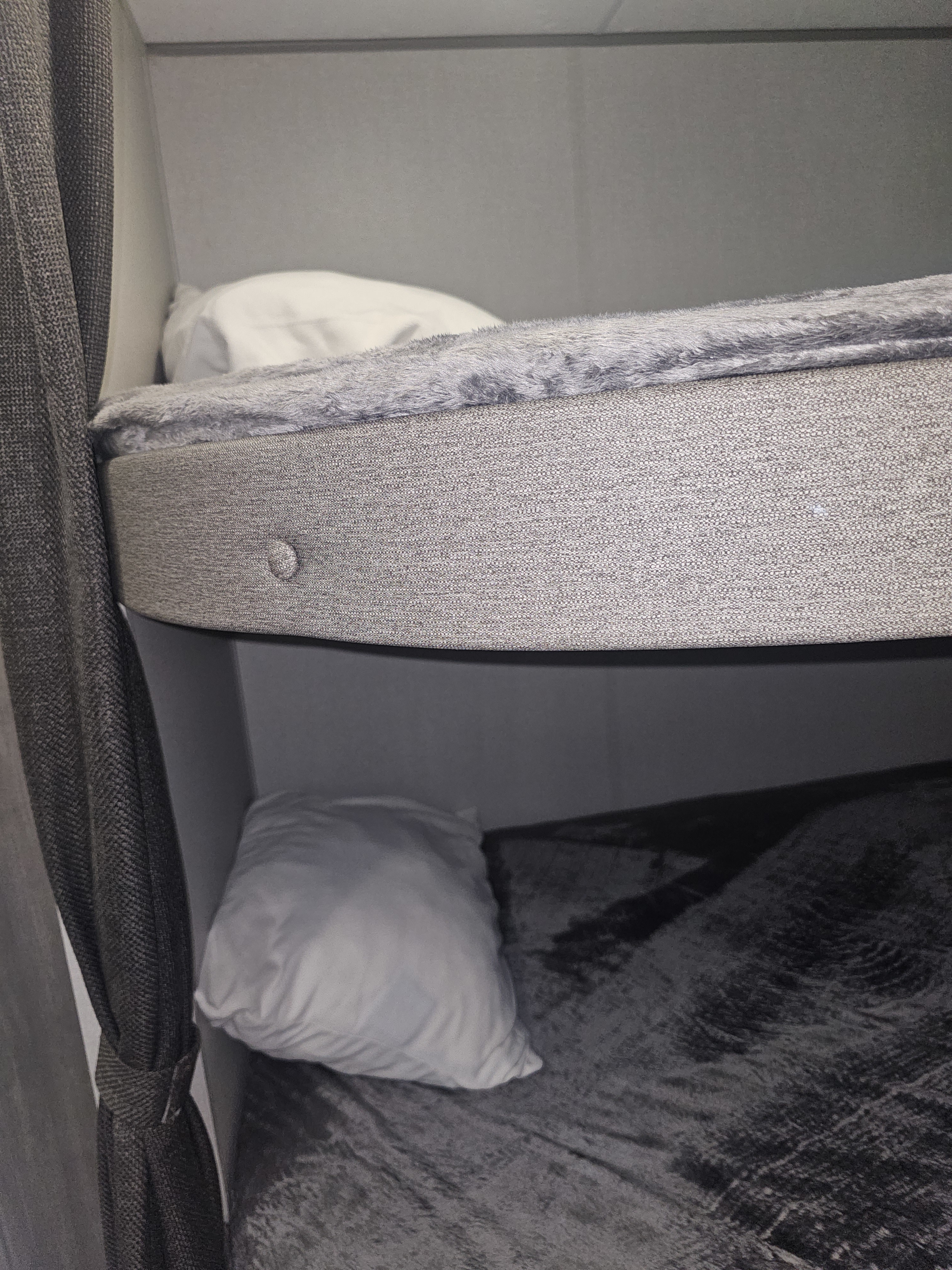RV rental: Interior bunk beds with gray fabric, white pillows, and soft blankets; a dark gray curtain hangs left.. Forest River Aurora Aurora 2026