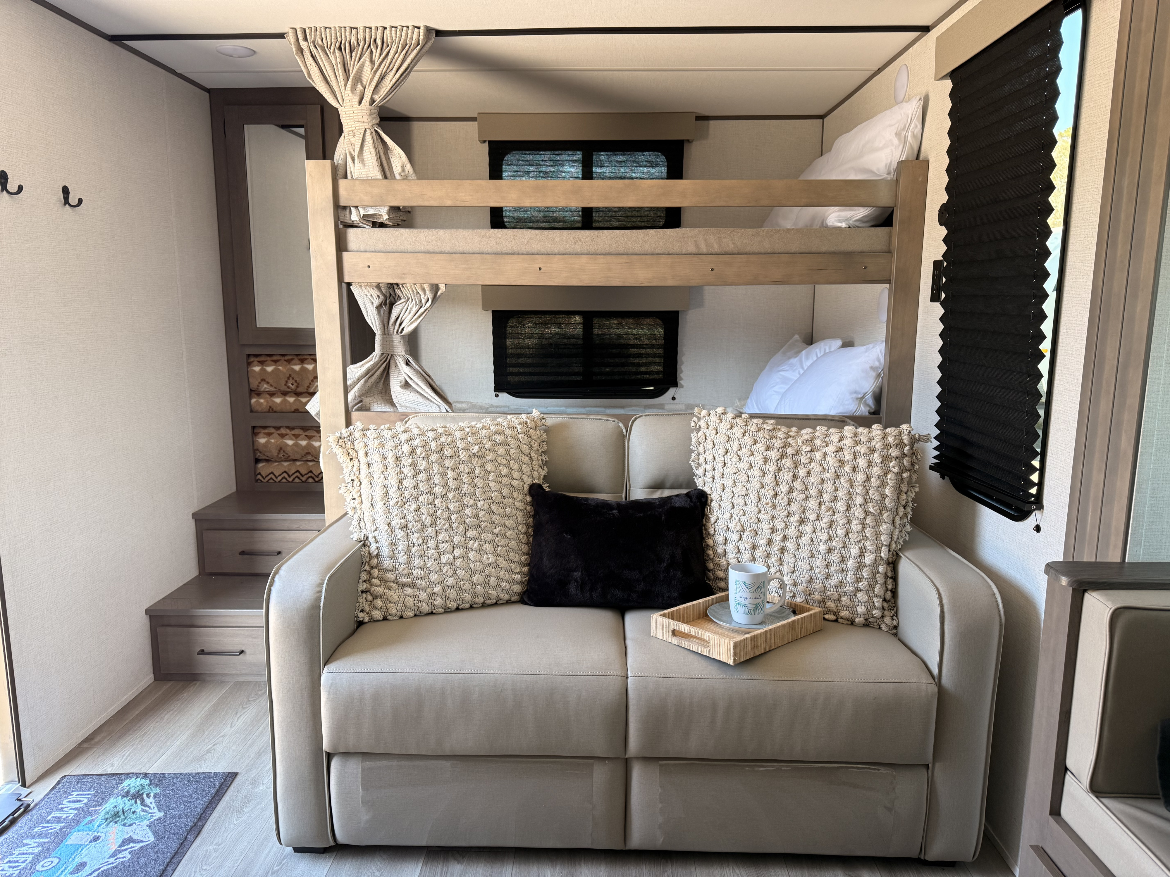 RV rental featuring cozy bunk beds over a comfy sofa, styled with decorative pillows and a side cabinet.. Grand Design Transcend 2025