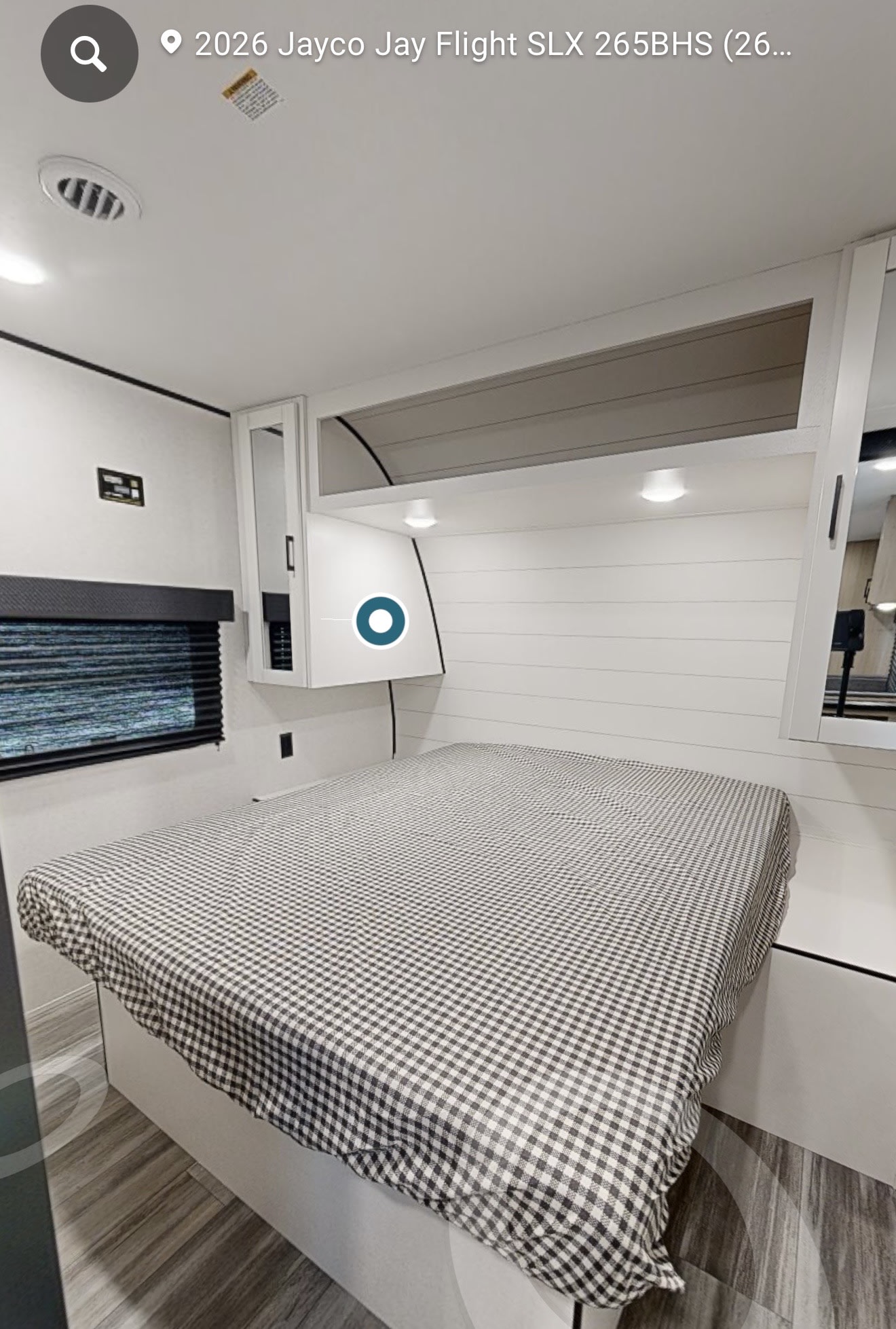 RV rental bedroom interior featuring a cozy bed with gingham cover, shiplap wall, and overhead storage.. Jayco Jay Flight SLX 2025