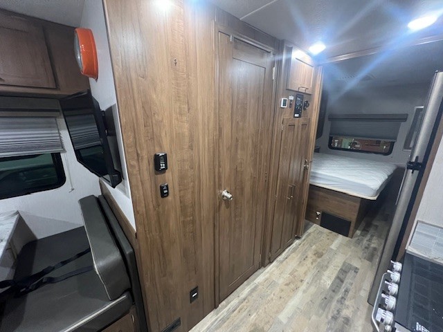 View of an rv rental's interior, featuring a bed, dining booth, TV, and kitchen area.. Forest River Coachmen Pursuit 2020