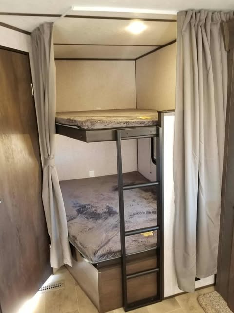 RV rental bunk beds with a ladder & privacy curtains. Ideal sleeping setup in a camper.. Dutchmen Coleman Lantern 2021