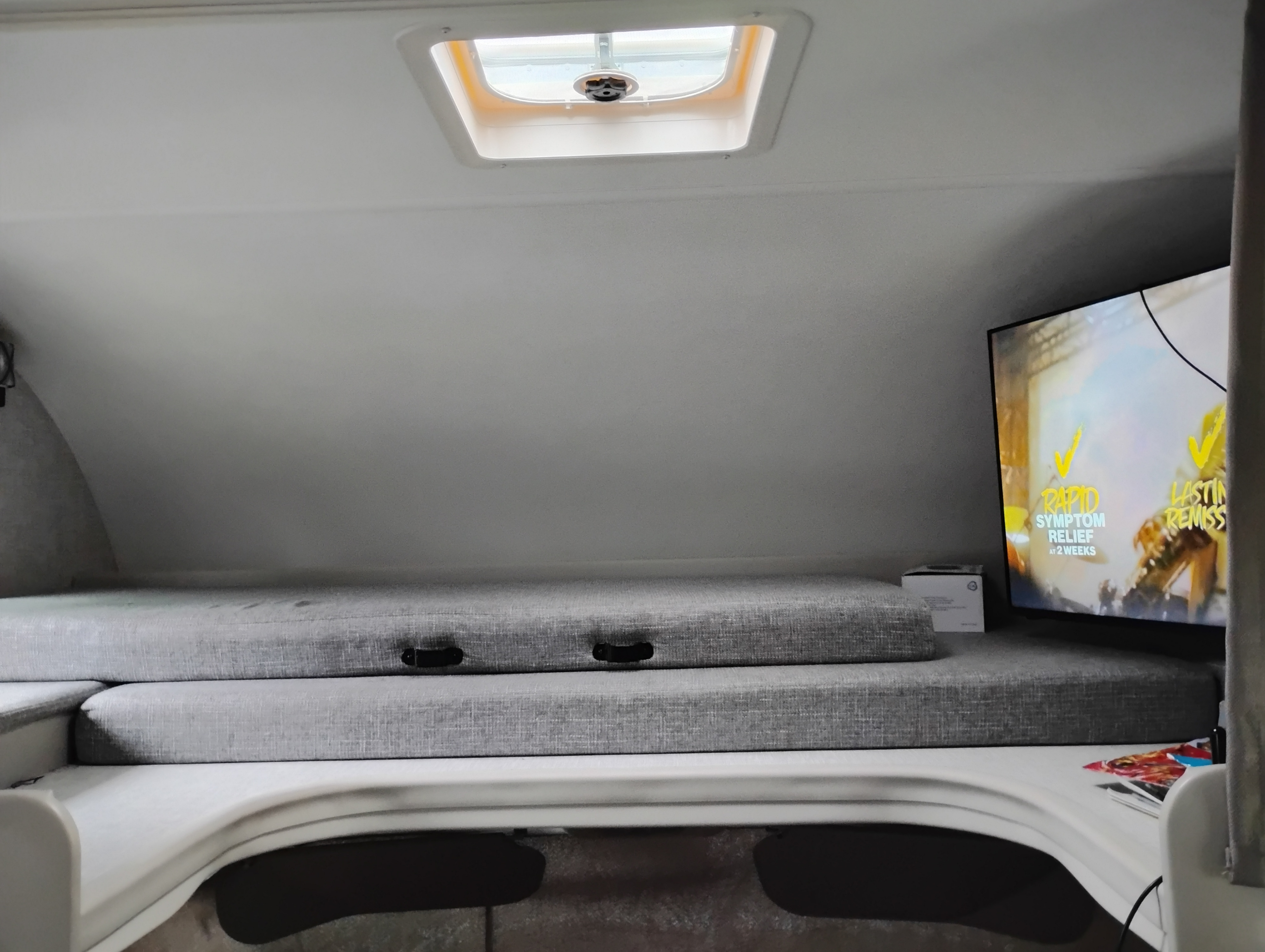 Inside an RV rental: a snug sleeping area with grey cushions, a TV, and a roof skylight. Ready for relaxing journeys.. 1ha3gsc7xrn001469 Thor motor coach 2025
