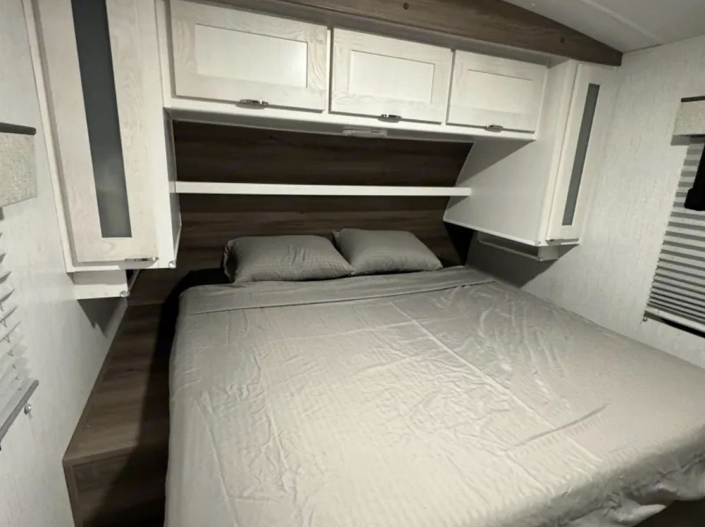 Explore this cozy RV rental bedroom featuring a full bed, overhead cabinets, and convenient bedside storage.. Cruiser RV MPG 2023